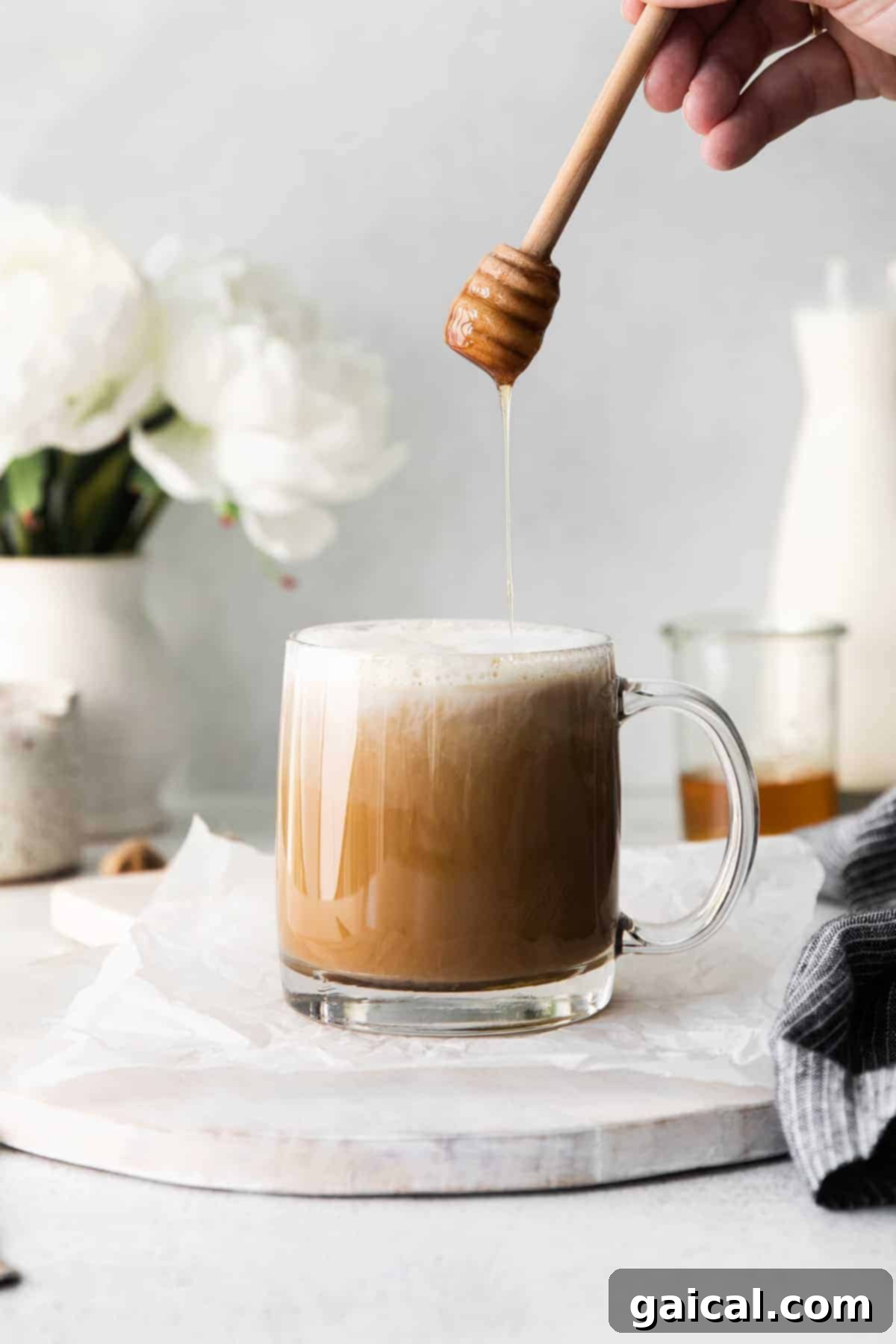 A delicious miel latte, finished with a honey drizzle. A finished miel latte in a clear glass mug, with a beautiful drizzle of honey cascading over the top and a sprinkle of cinnamon.