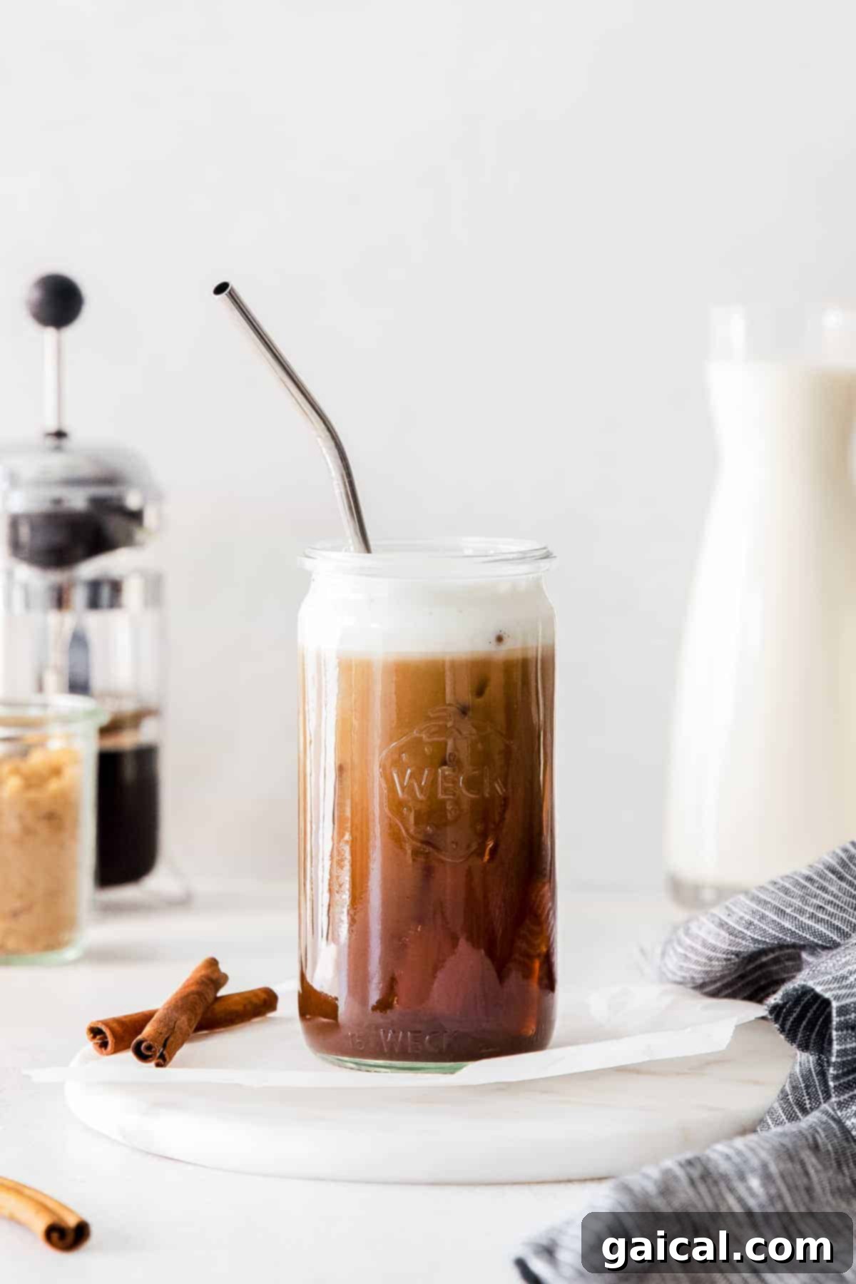 A glass of homemade iced brown sugar oat milk shaken espresso with a straw, capturing the layered look of espresso and oat milk.