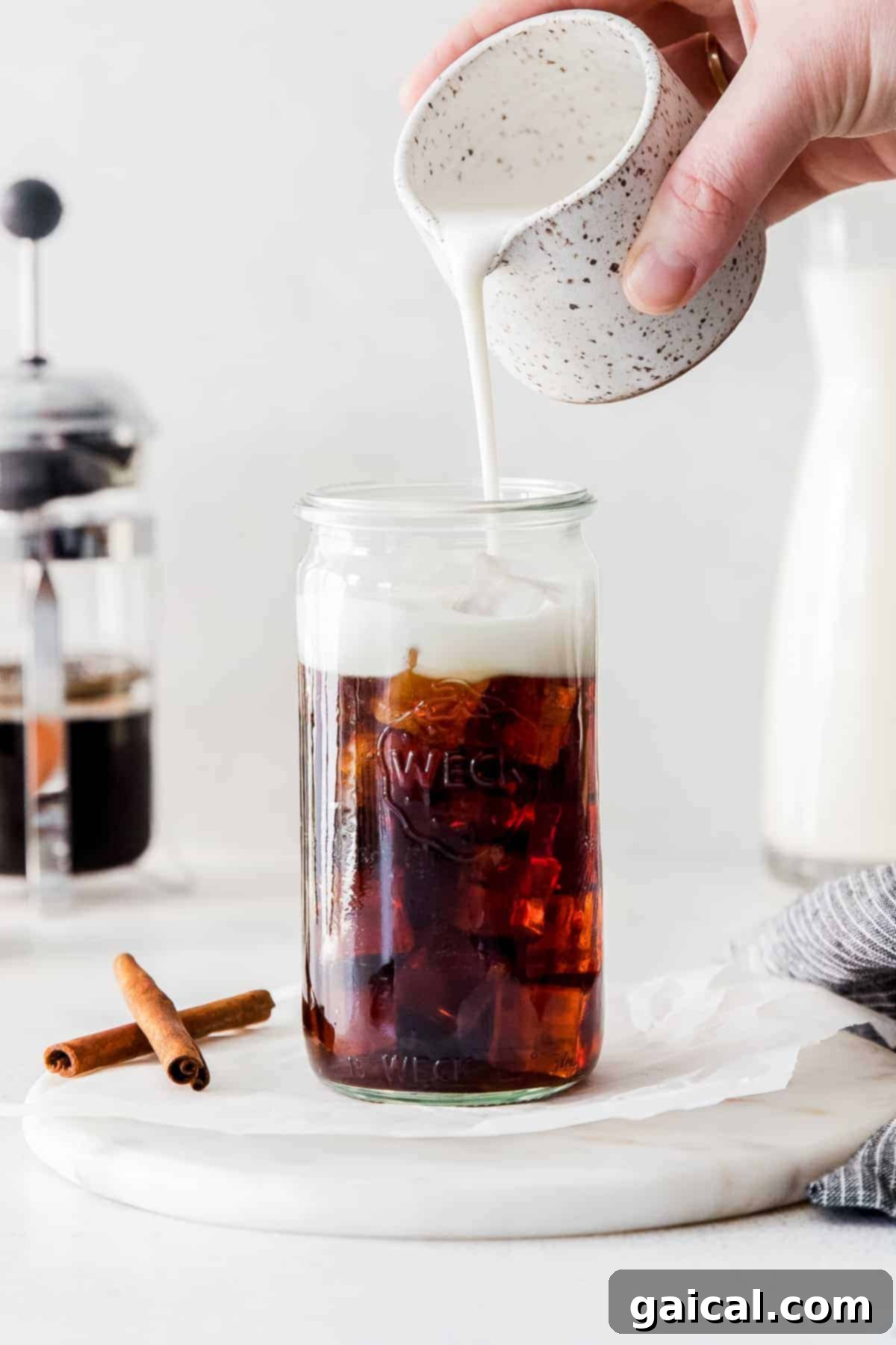 Creamy oat milk being poured into a clear glass, showing its smooth texture.