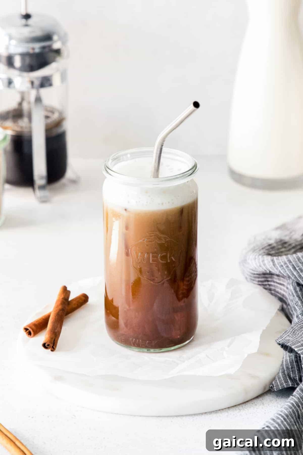 A tall glass of Iced Brown Sugar Oat Milk Shaken Espresso with a straw, showcasing the perfect layers and frothy top.