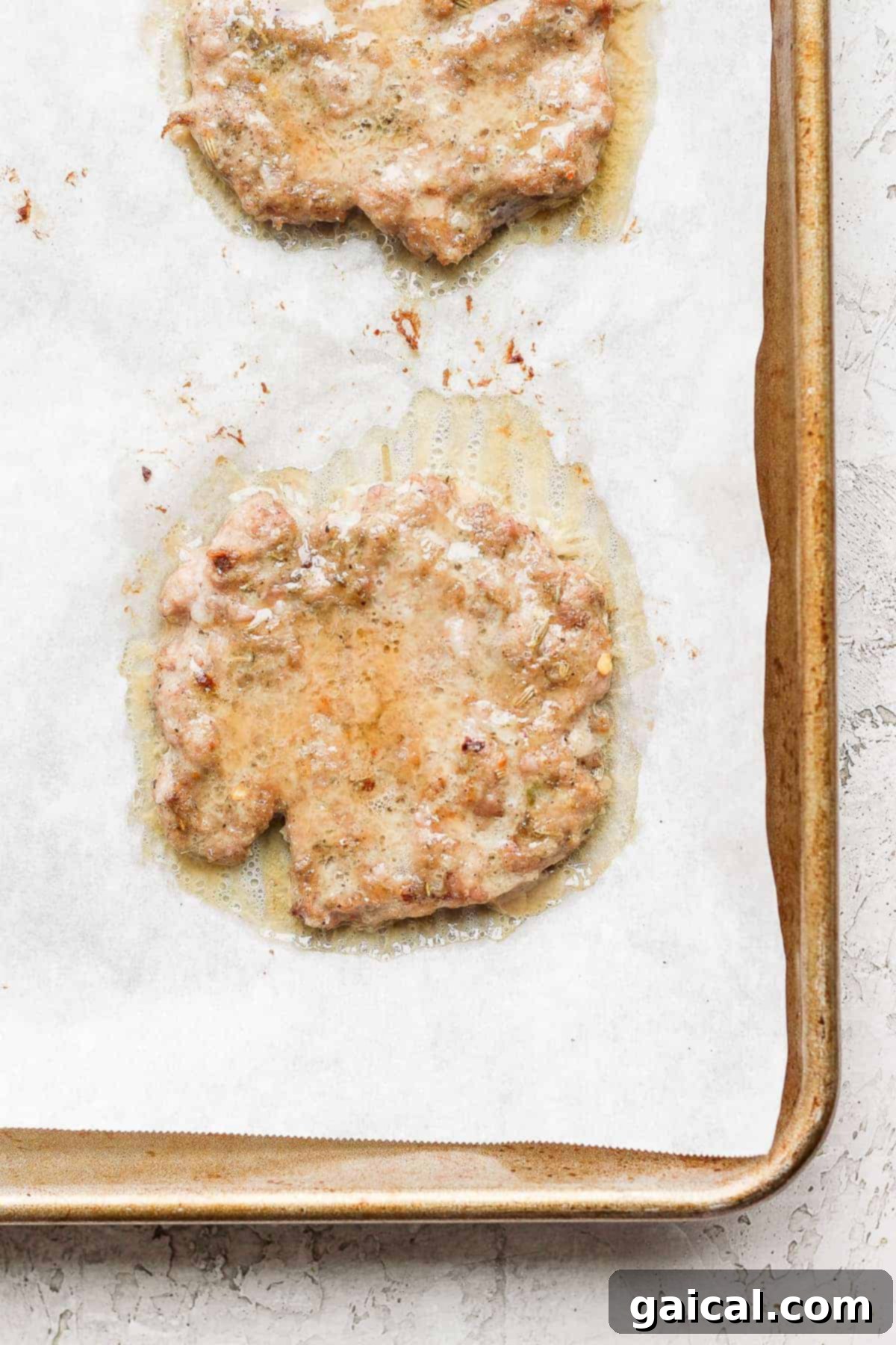 Breakfast sausage patties baking on a parchment-lined baking sheet in the oven.