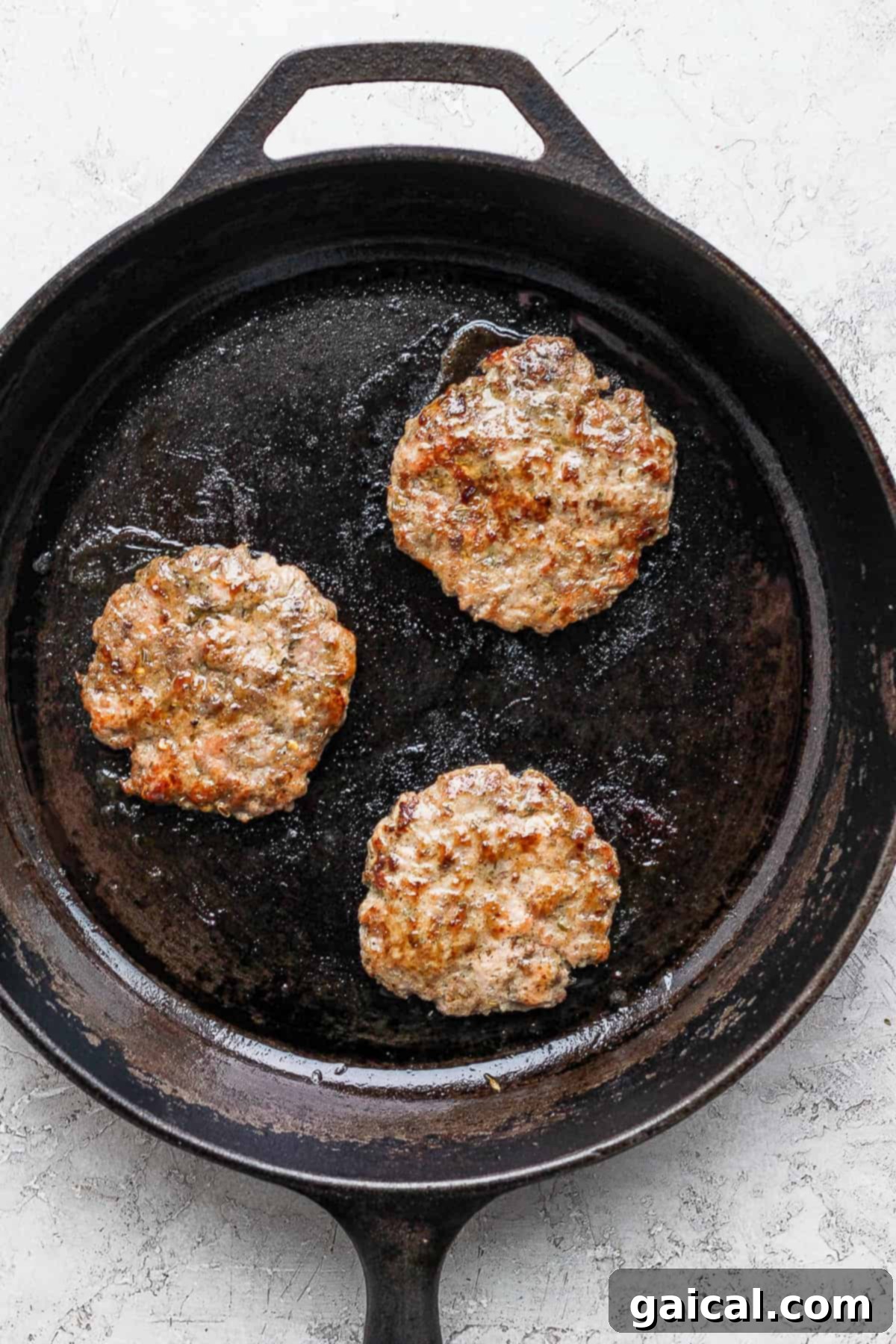 Sizzling breakfast sausage cooking in a cast iron skillet.