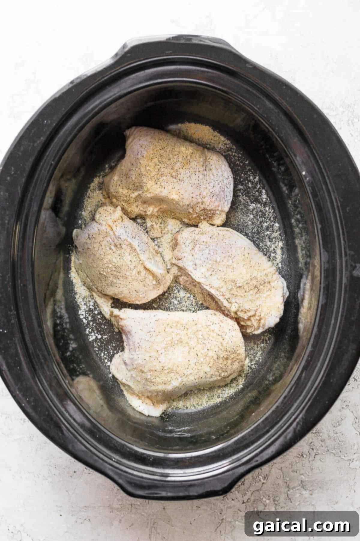Soul-Warming Slow Cooker Chicken and Dumplings 4 Spiced bone-in chicken thigh placed inside a slow cooker with other vegetables and broth.