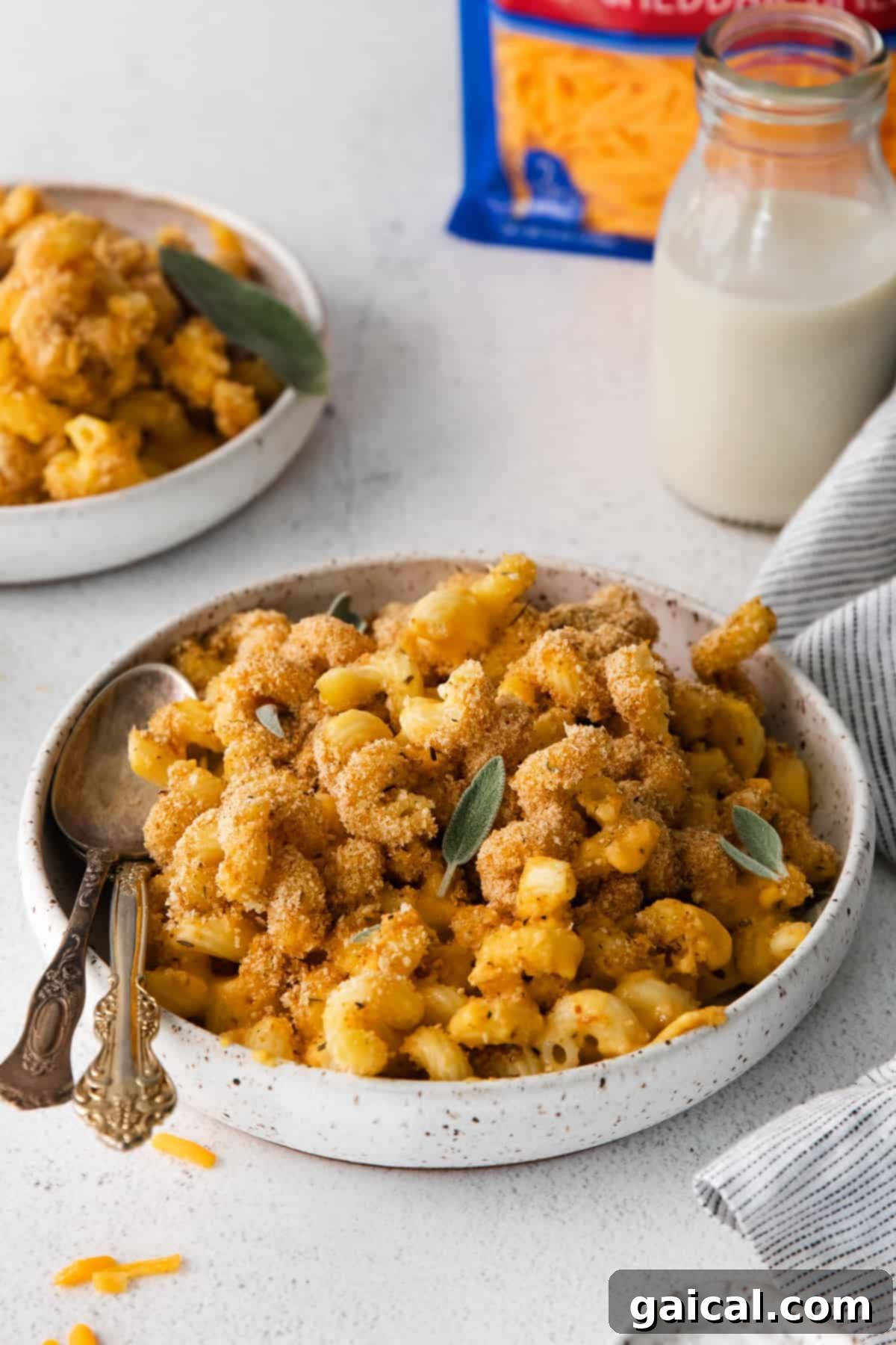 Golden Butternut Mac 6 A serving of butternut squash mac and cheese in a white bowl, garnished with fresh sage leaves.