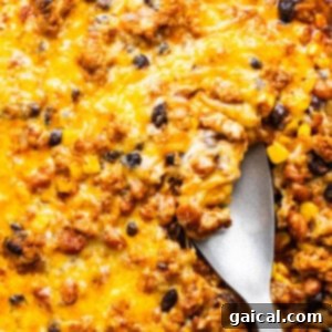 Vibrant Healthy Enchilada Dip 10 A skillet with baked cheesy casserole containing ground meat, black beans, and corn.