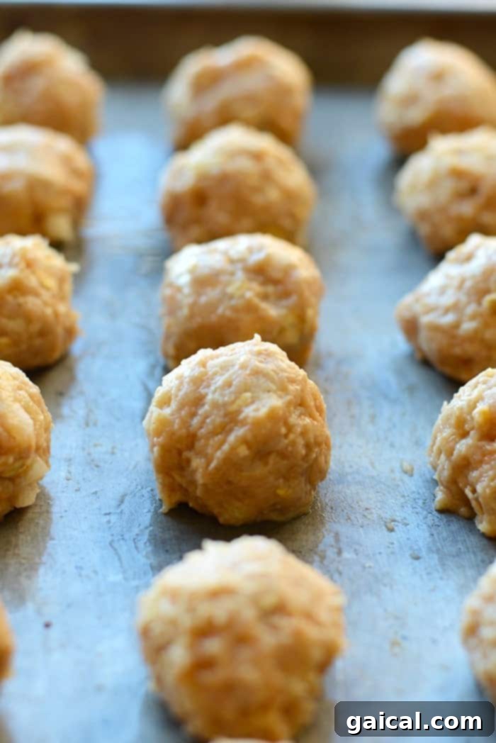 Prepped Chicken Meatballs for Baking Baking sheet with raw chicken meatballs before cooking