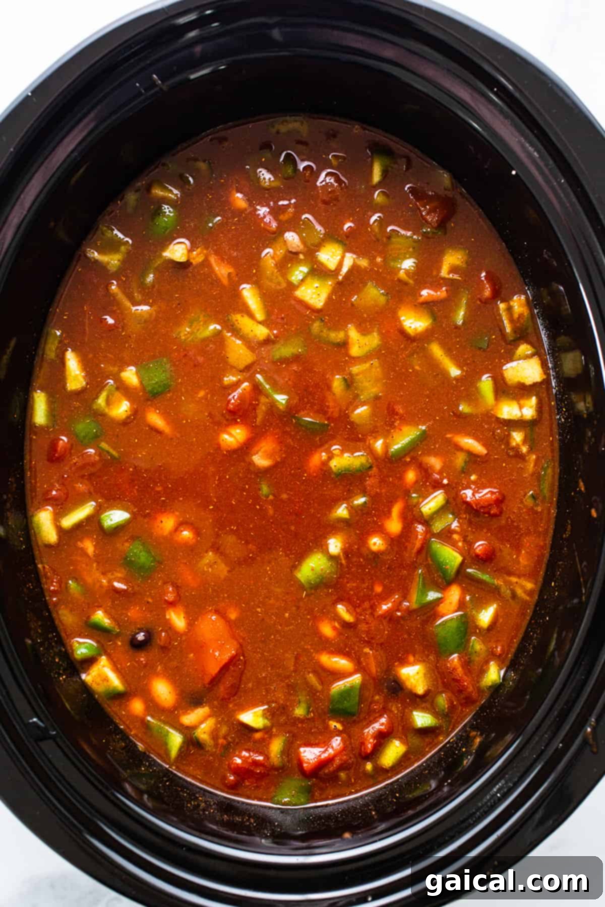 A large pot of chicken enchilada soup simmering, with a ladle ready to serve, showcasing its rich texture.