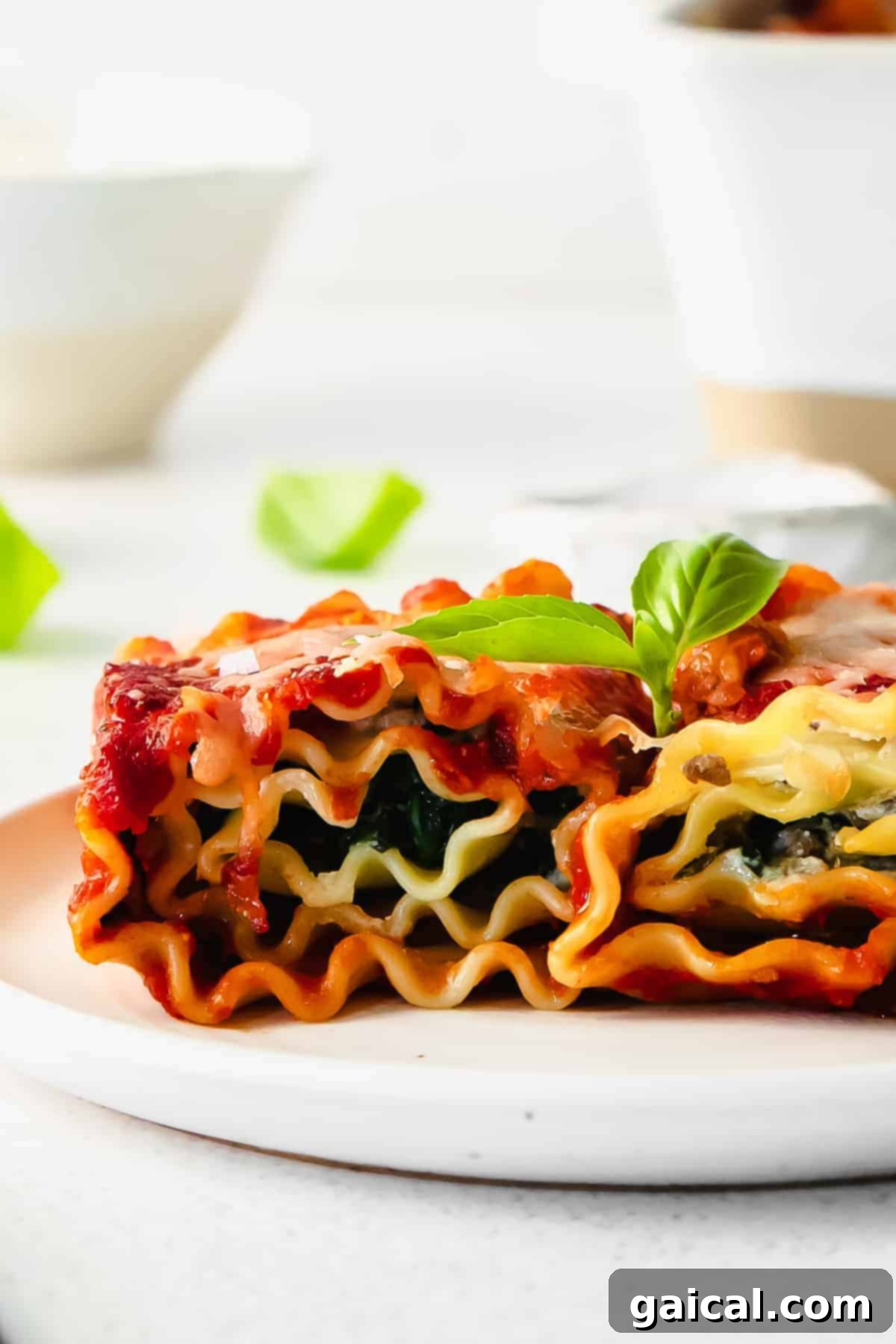 Lasagna Pinwheels 2 Two perfectly baked lasagna roll-ups on a white plate, garnished with fresh basil, showcasing the melted cheese and rich marinara.