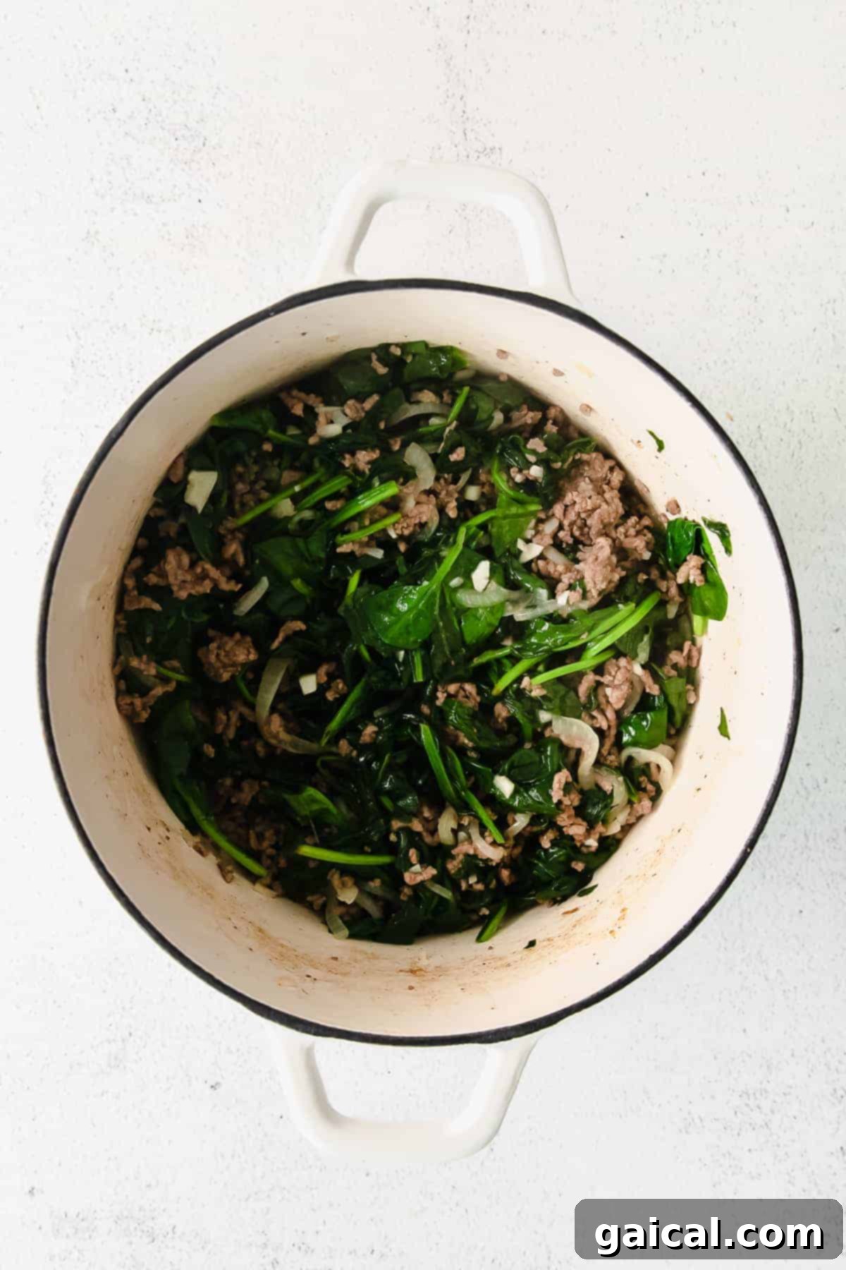 Lasagna Pinwheels 4 Sautéed ground meat, fresh spinach, and onions cooking together in a large Dutch oven, creating the flavorful base for the lasagna roll-up filling.