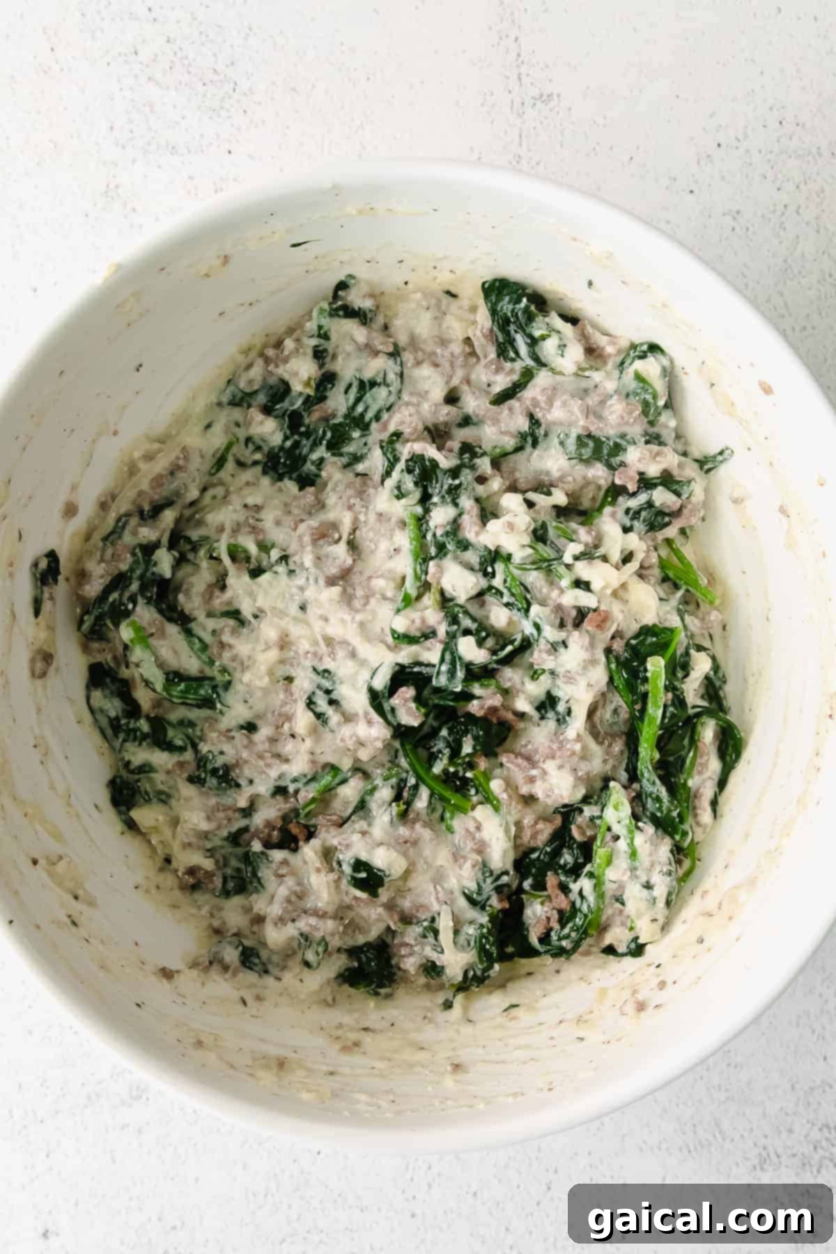Lasagna Pinwheels 5 A large mixing bowl filled with the rich and creamy lasagna roll up filling, a delectable blend of cheeses, seasoned meat, and spinach, ready for assembly.