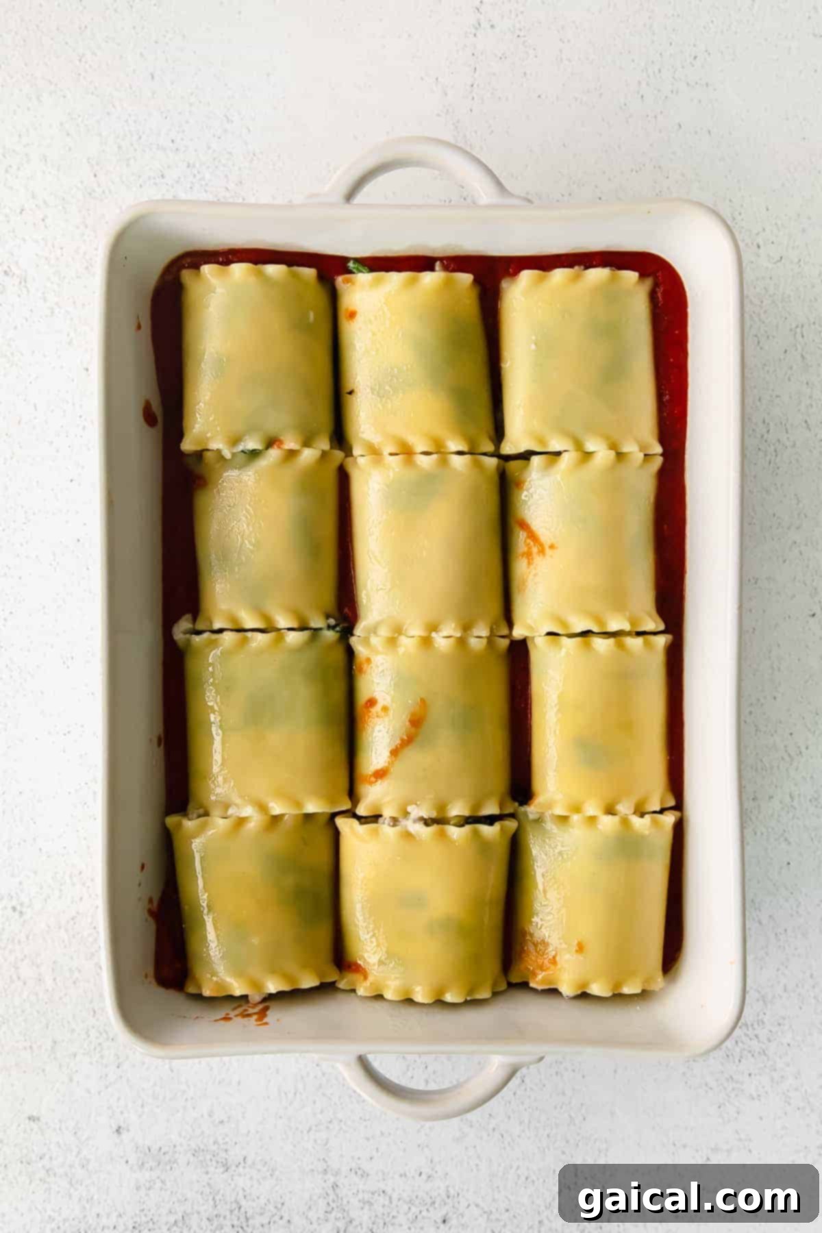 Lasagna Pinwheels 8 Freshly baked lasagna roll-ups in a white casserole dish, garnished with fresh herbs, ready to be served.
