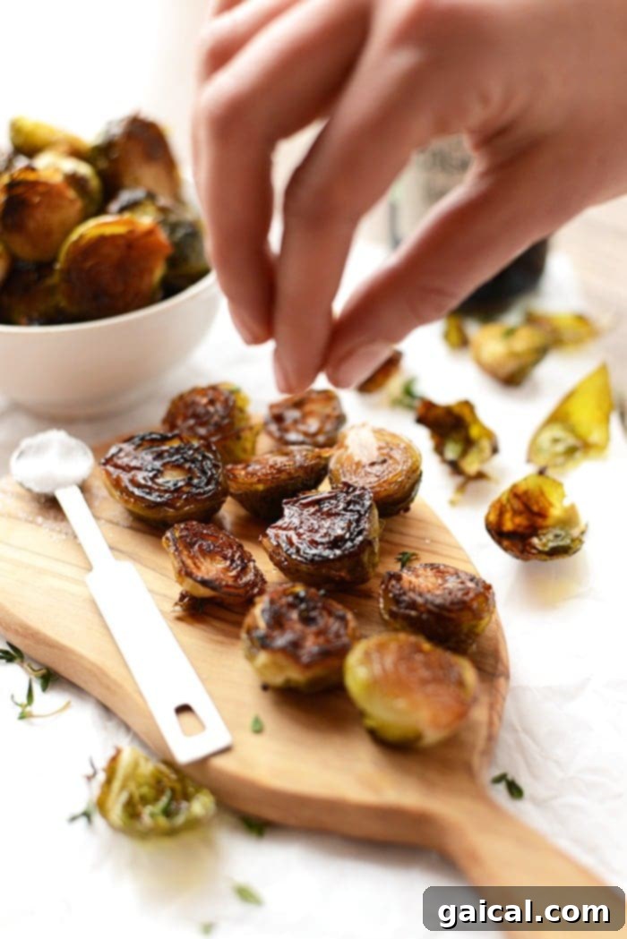 Roasted Brussels sprouts being sprinkled with sea salt for ultimate flavor and crunch.
