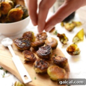 Perfectly roasted Brussels sprouts garnished with sea salt on a wooden cutting board.