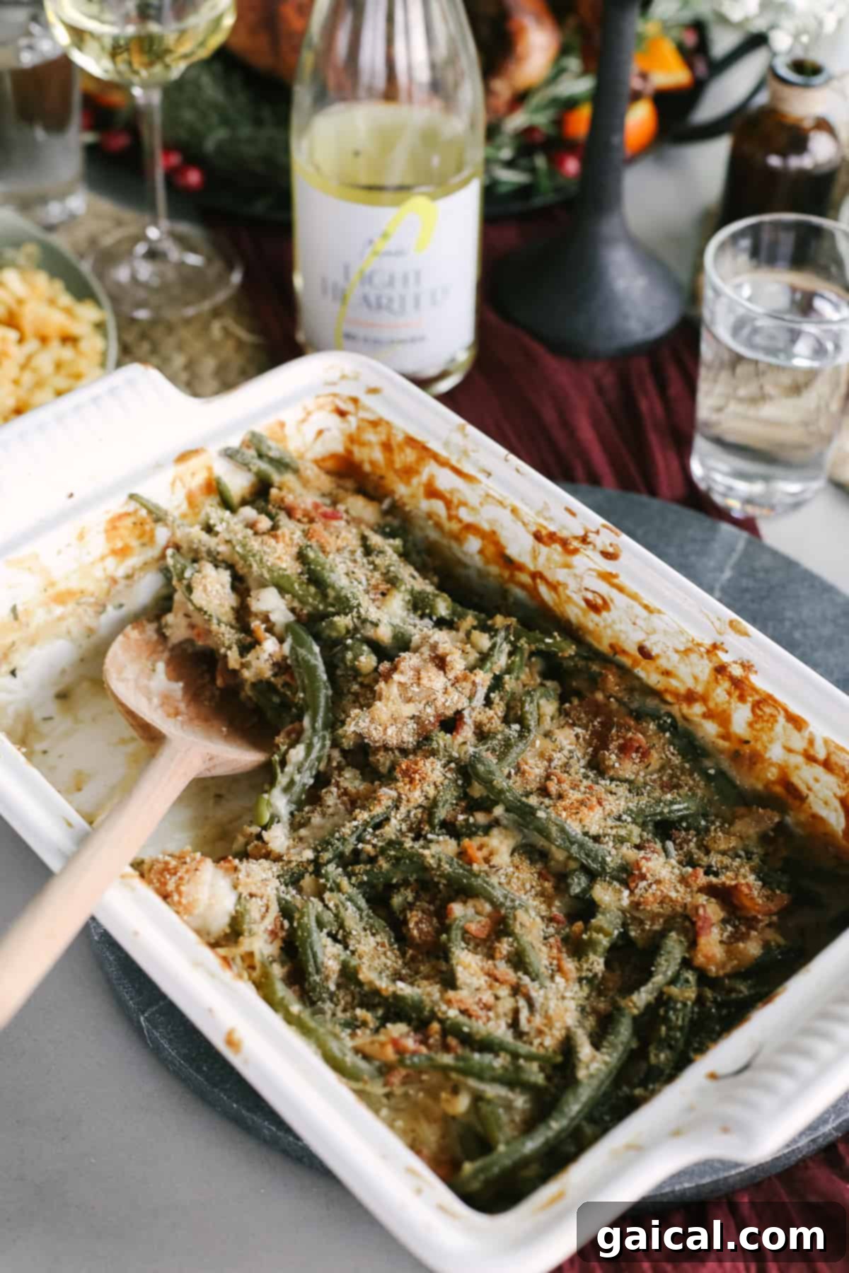 A bubbling casserole dish filled with homemade green bean casserole, generously topped with crispy bacon.