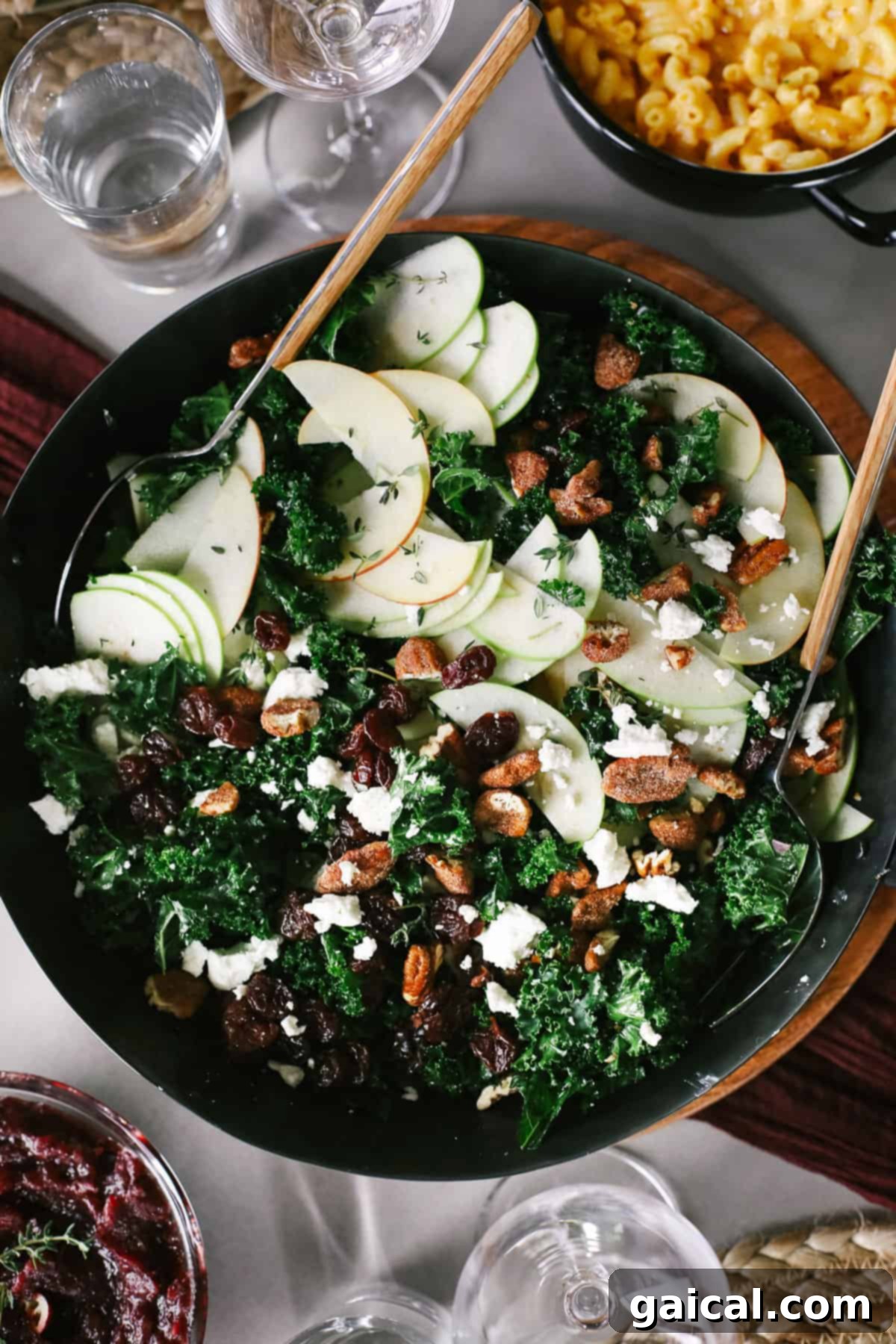 A vibrant Thanksgiving salad in a large serving bowl, featuring kale, apples, pecans, goat cheese, and dried cherries.