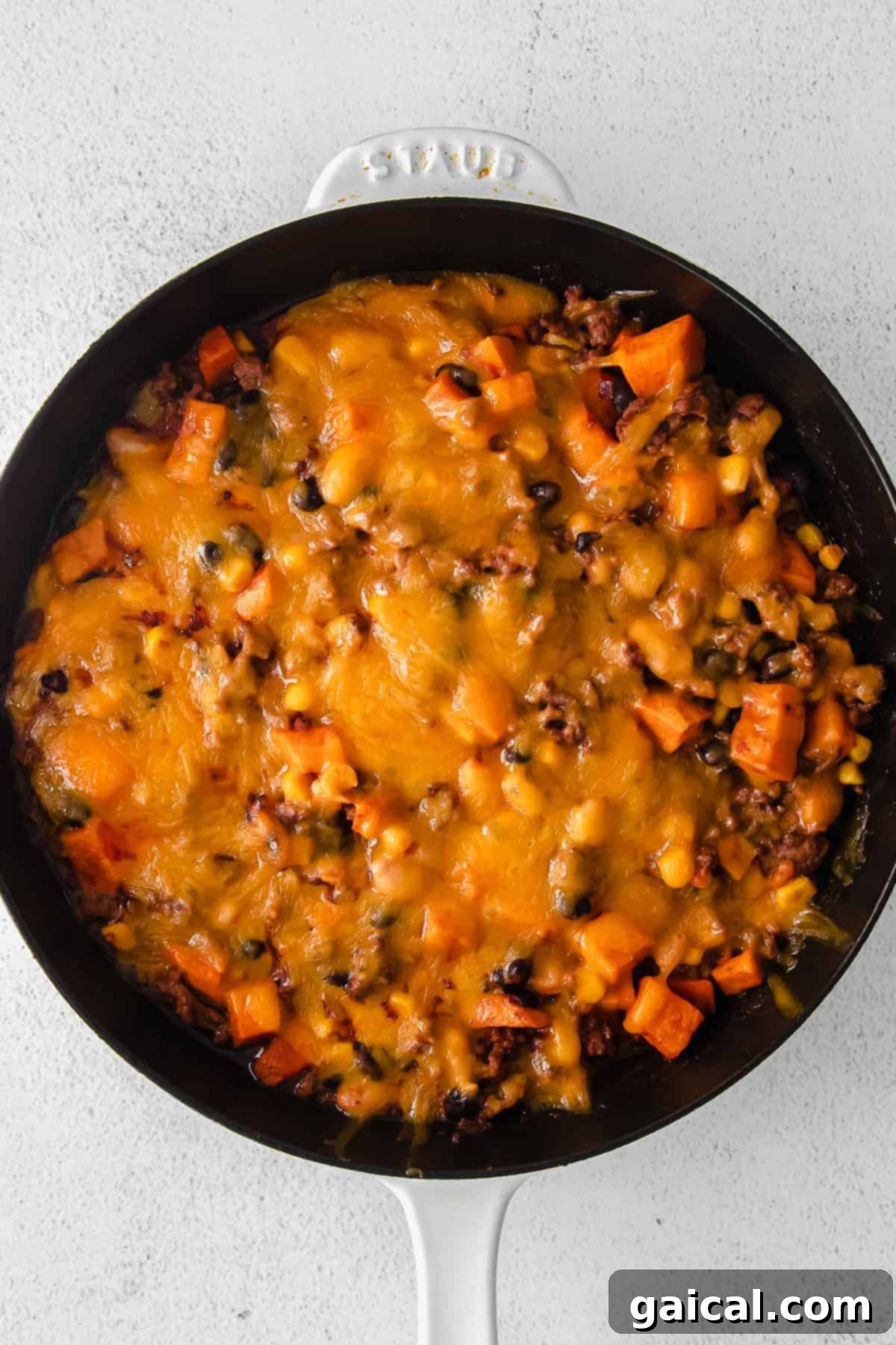 This turkey sweet potato enchilada skillet is a true one pot meal that comes together in 30 minutes flat. Enjoy this easy weeknight dinner tonight! turkey sweet potato enchilada skillet topped with melted shredded cheese