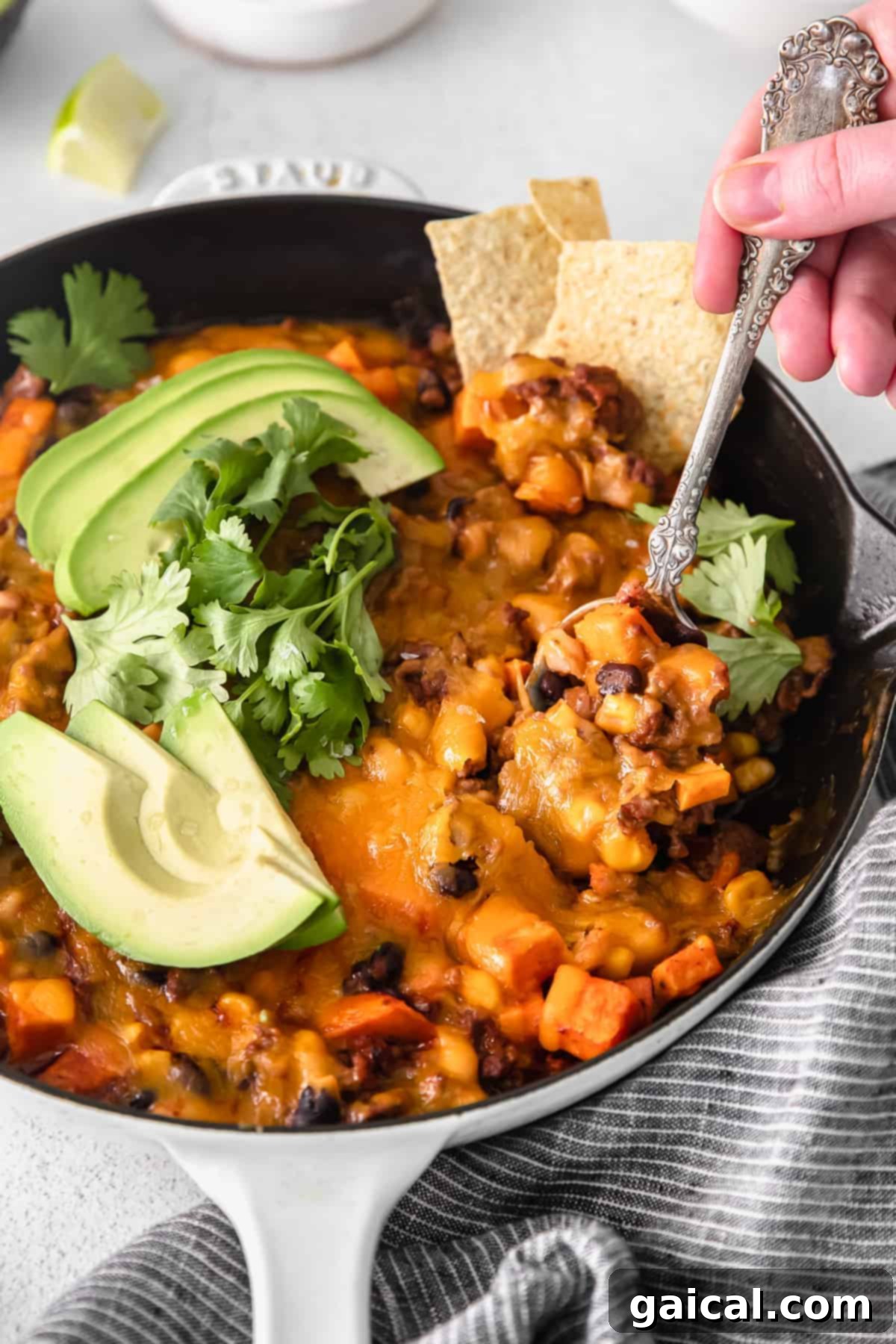 This turkey sweet potato enchilada skillet is a true one pot meal that comes together in 30 minutes flat. Enjoy this easy weeknight dinner tonight! turkey sweet potato enchilada skillet on a spoon