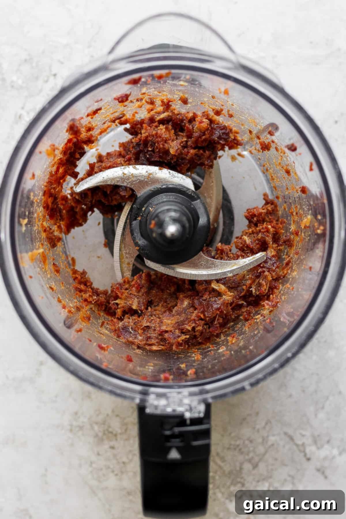 Salted Caramel Date Bites 3 A food processor blending soft Medjool dates into a rich, golden caramel paste, showcasing the initial step of making the date caramel.