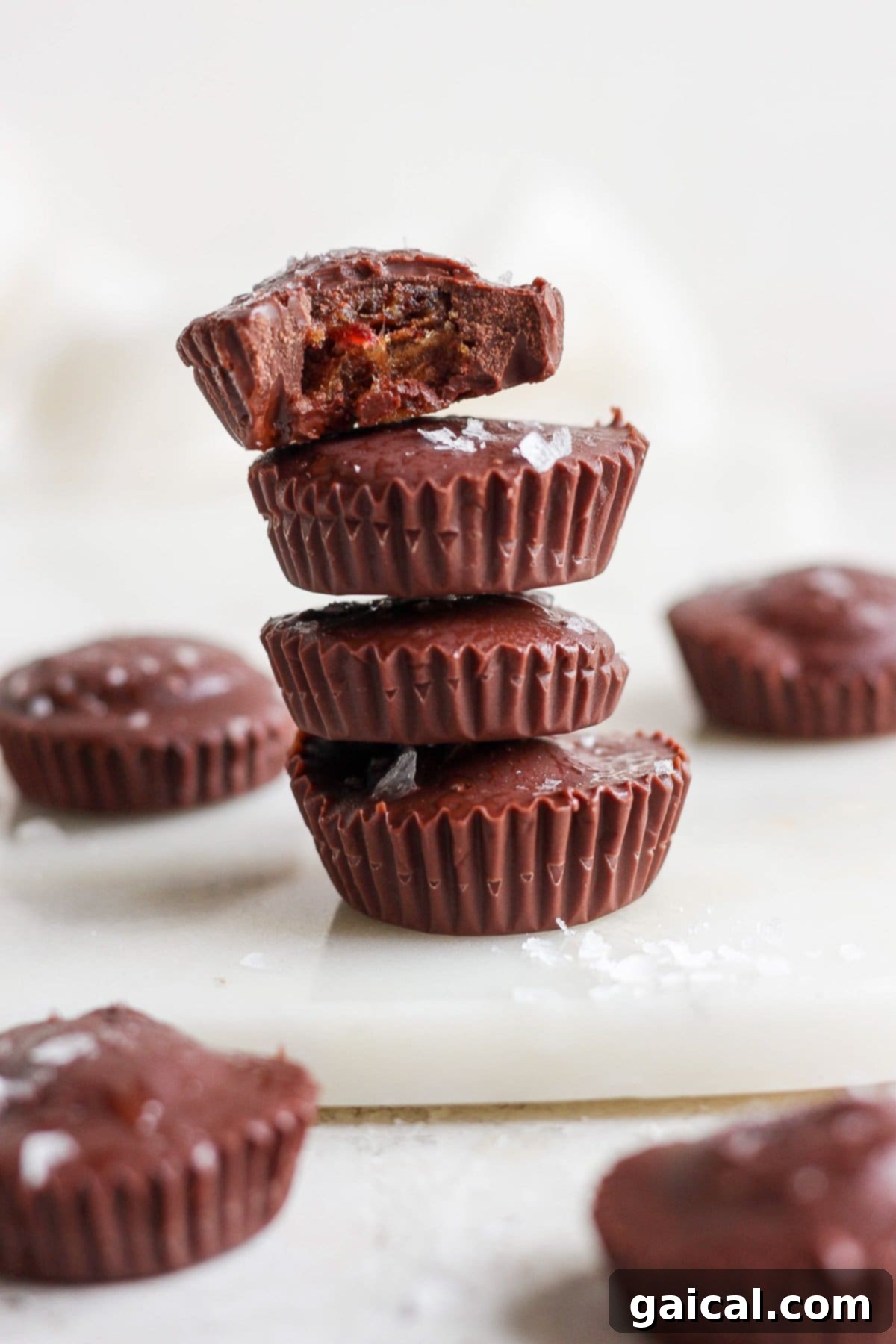 Salted Caramel Date Bites 9 A beautifully arranged stack of homemade salted caramel date cups on a rustic wooden cutting board, ready for storage or serving.