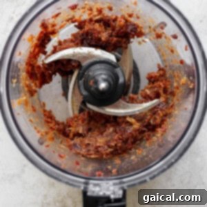 Salted Caramel Date Bites 5 Close-up of a food processor actively blending Medjool dates into a smooth, thick caramel paste, central to the date cup recipe.