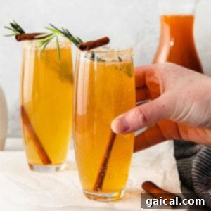 Effortless Mimosa Perfection 2 A vibrant apple cider mimosa cocktail garnished with cinnamon sticks and apple slices, perfect for autumn celebrations.