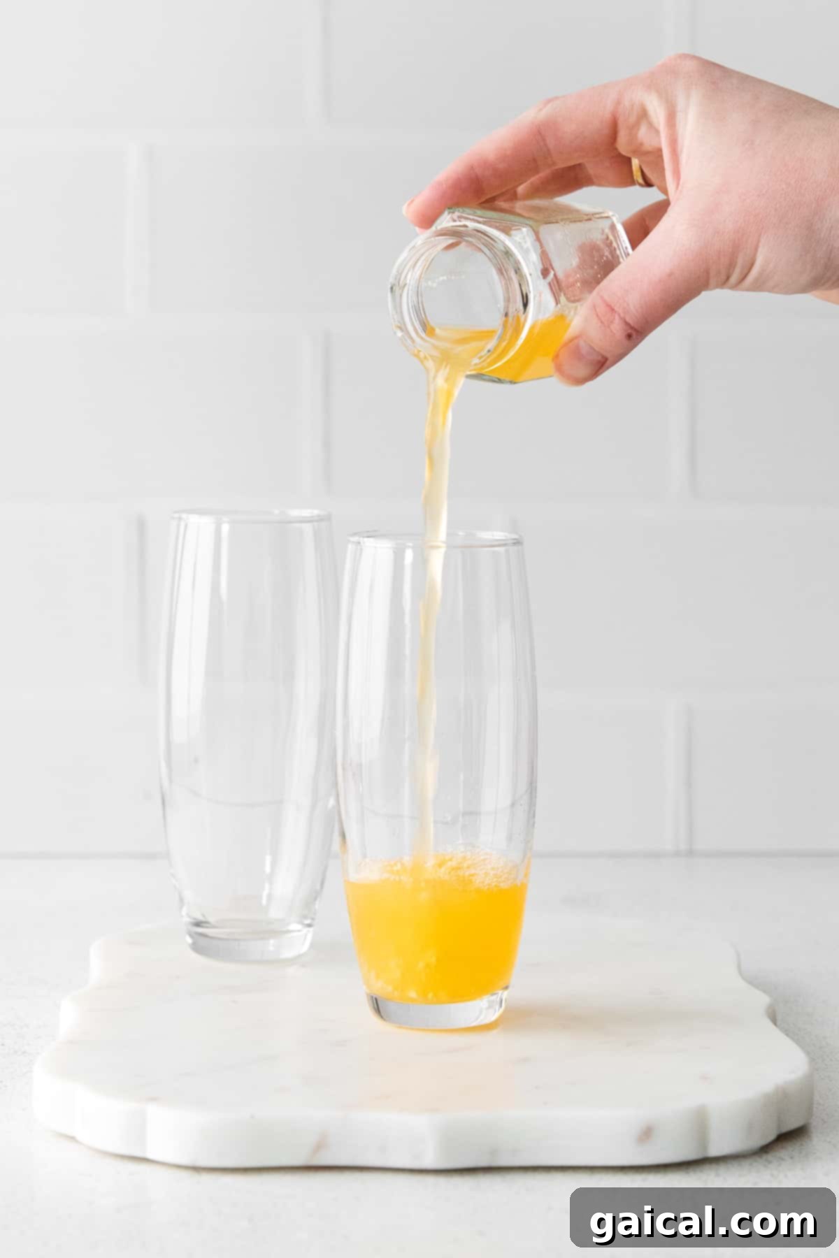 Pouring Orange Juice for Mimosas Freshly squeezed orange juice being carefully poured into stemless champagne flutes, ensuring the perfect base for mimosas.