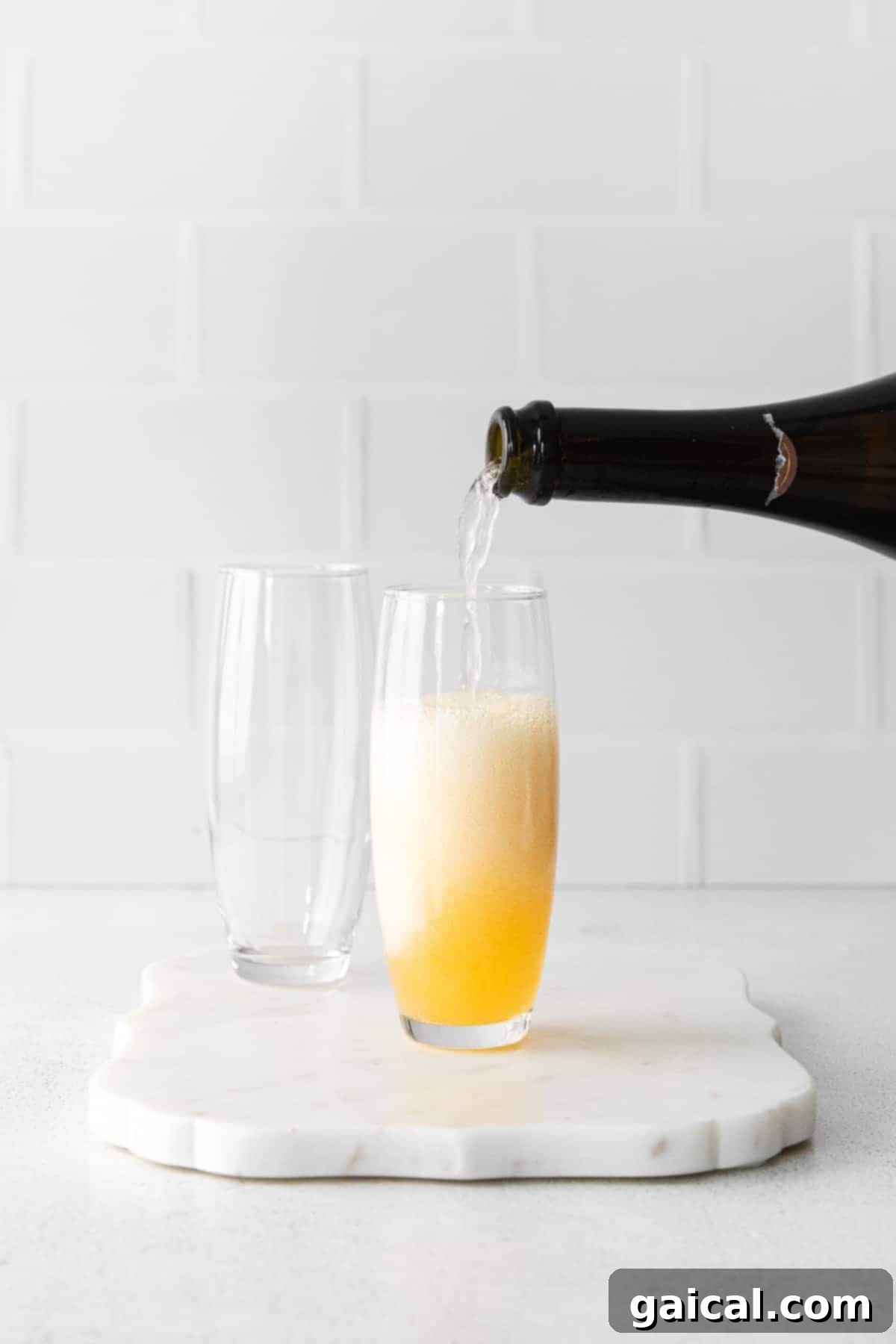 Pouring Champagne for Mimosa Effervescent champagne being carefully poured into a flute already containing orange juice, forming a classic mimosa.
