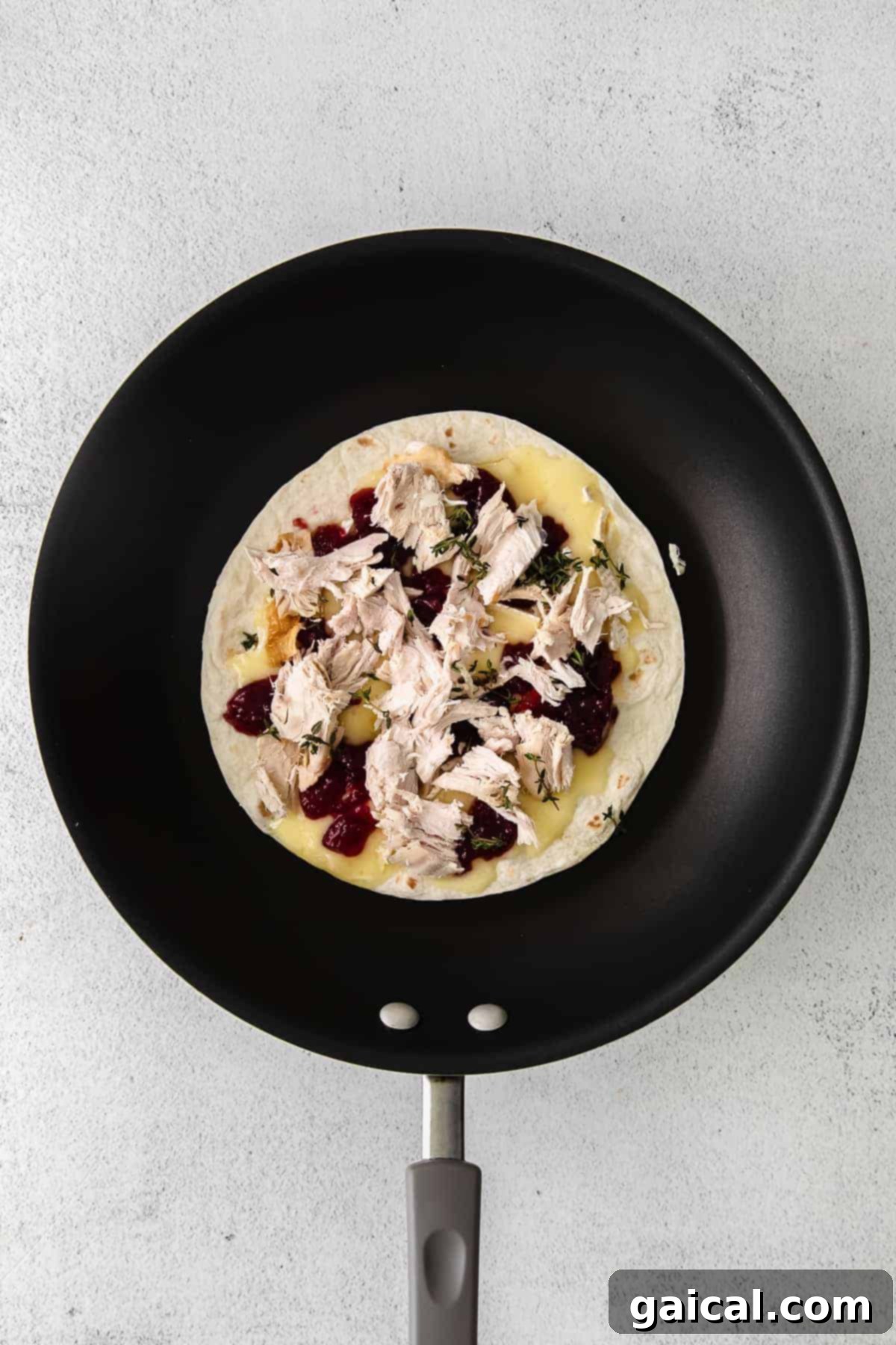 Watch your Thanksgiving Turkey Quesadilla get perfectly golden and crispy in the skillet! Leftover Thanksgiving Turkey Quesadilla cooking in a skillet on the stovetop
