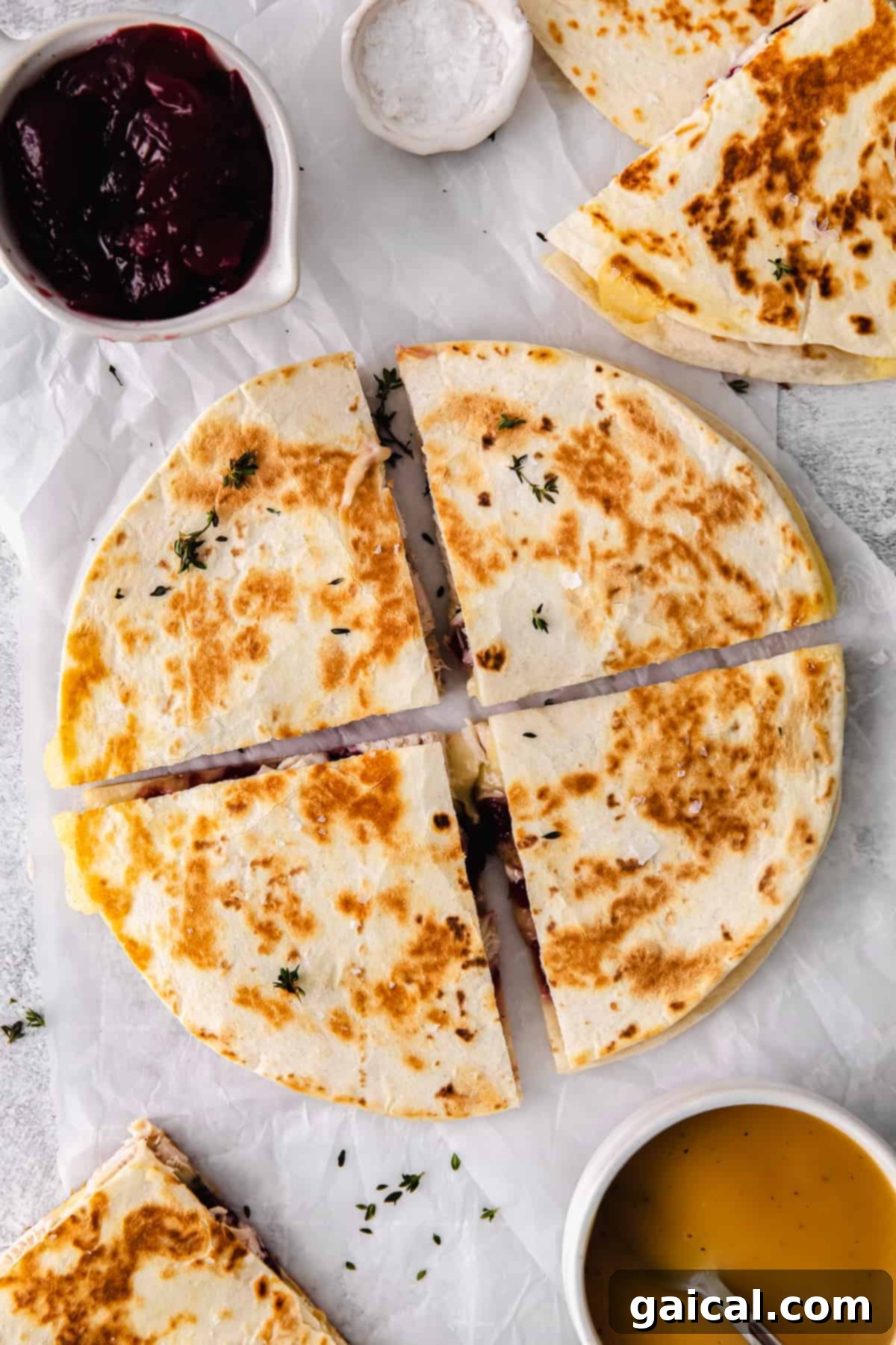 Serve up these delicious Turkey Quesadilla slices for an unforgettable meal! Leftover Thanksgiving Turkey Quesadilla cut into four equal slices, served on a white plate