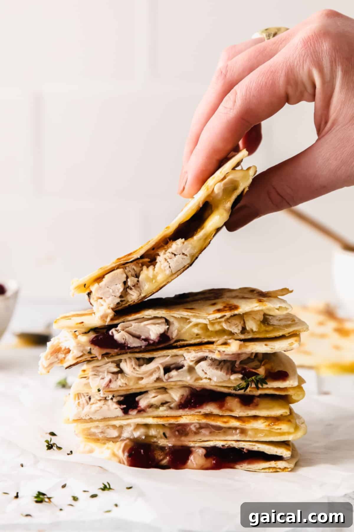 A delicious stack of Leftover Thanksgiving Turkey Quesadillas ready to be devoured! Leftover Thanksgiving Turkey Quesadillas stacked four slices high on a white plate