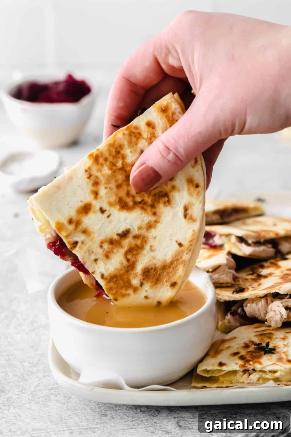 The ultimate dip: Thanksgiving Turkey Quesadilla in savory gravy! Leftover Thanksgiving Turkey Quesadilla being dipped into a small bowl of gravy
