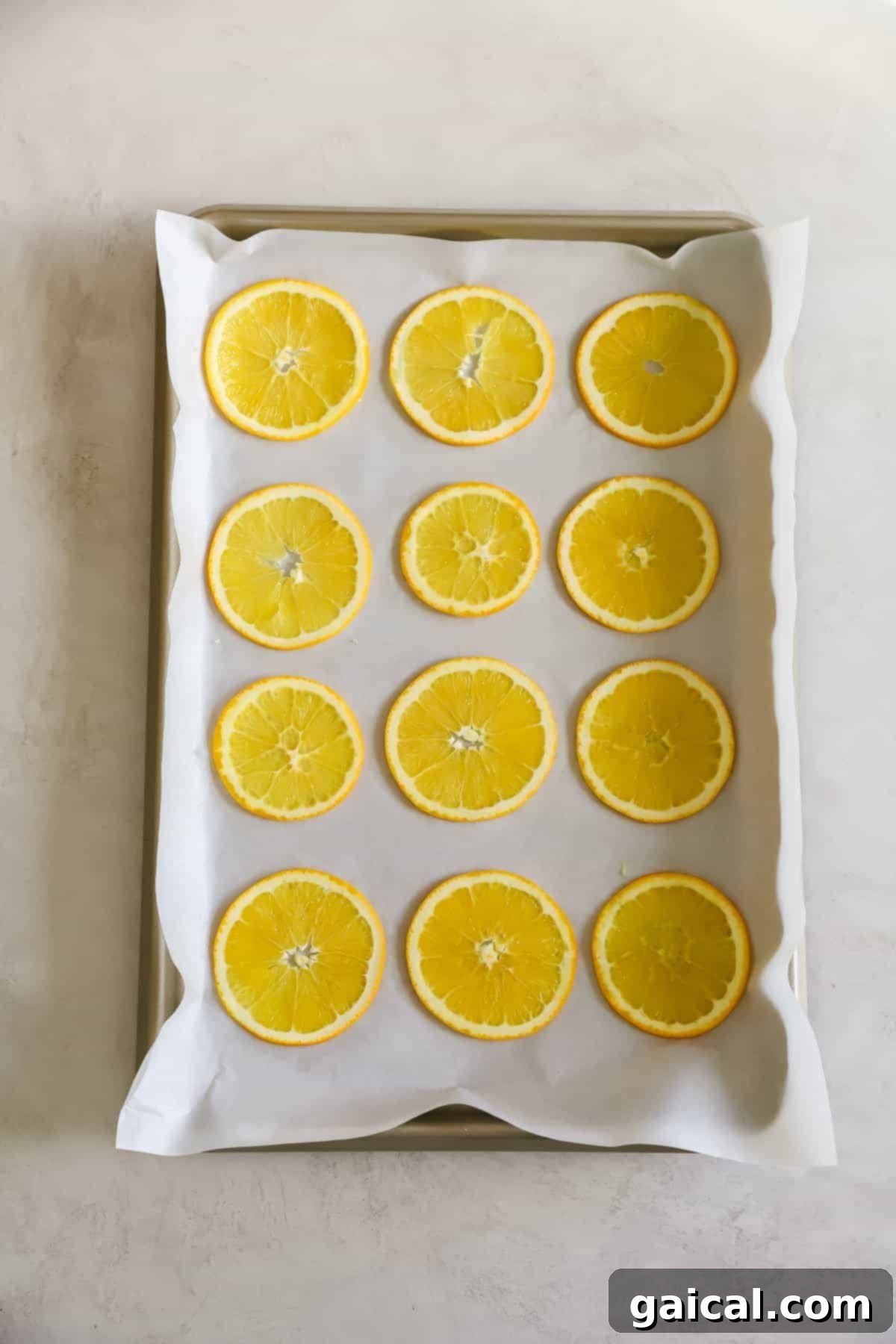 Dried orange garland is such a fun DIY holiday decoration that only requires 1 ingredient - oranges! Thinly sliced orange rounds meticulously arranged in a single layer on a parchment-lined baking sheet, ready for the oven.