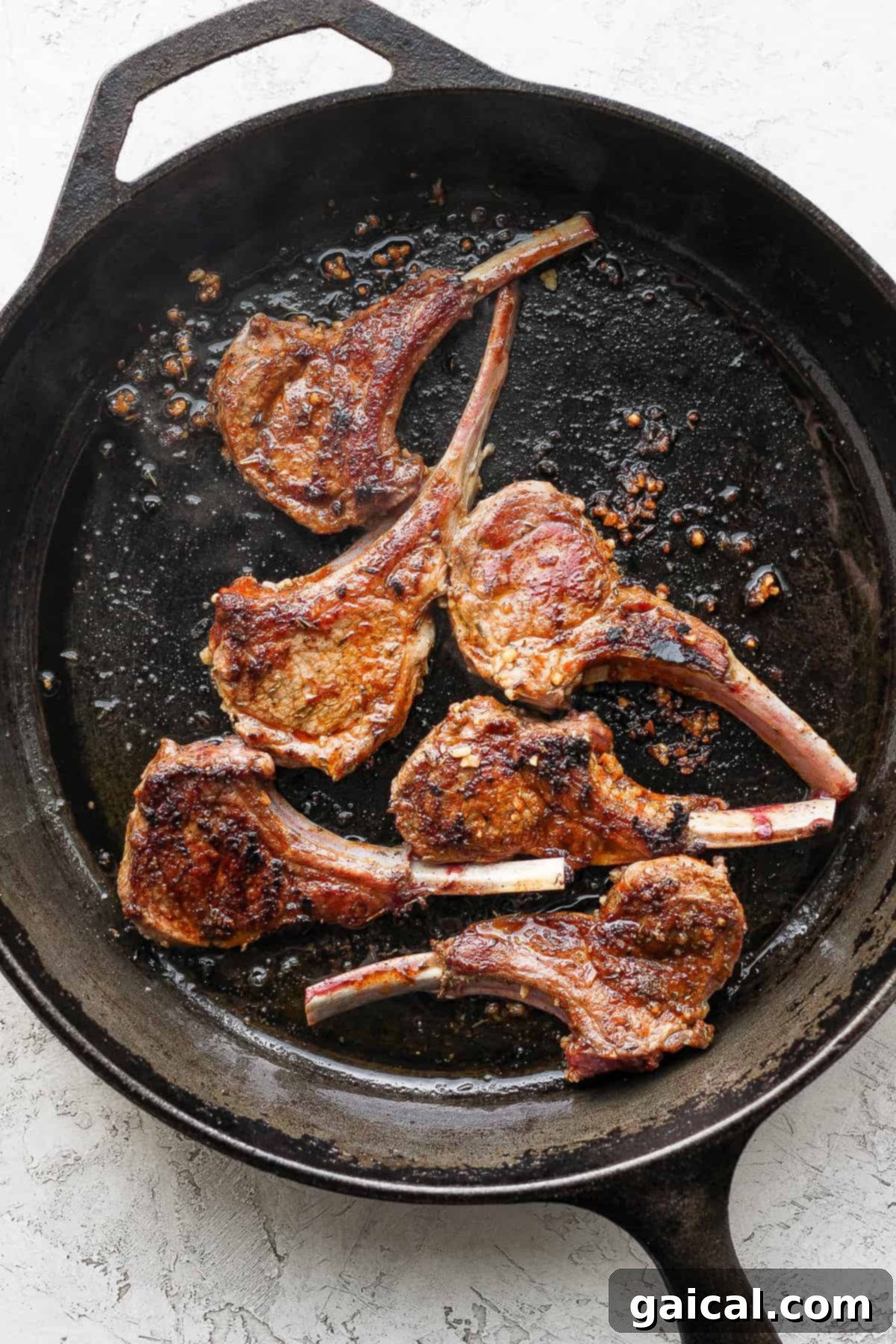 Pan-Seared Lamb Chops Sizzling in a Cast Iron Skillet Sizzling pan-seared lamb chops cooking to perfection in a hot cast iron skillet.