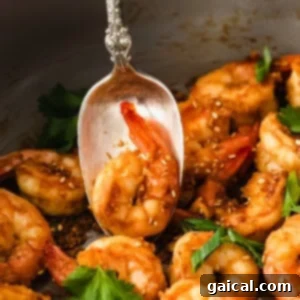 Perfectly cooked, vibrant sautéed shrimp on a spoon, ready to be sampled.