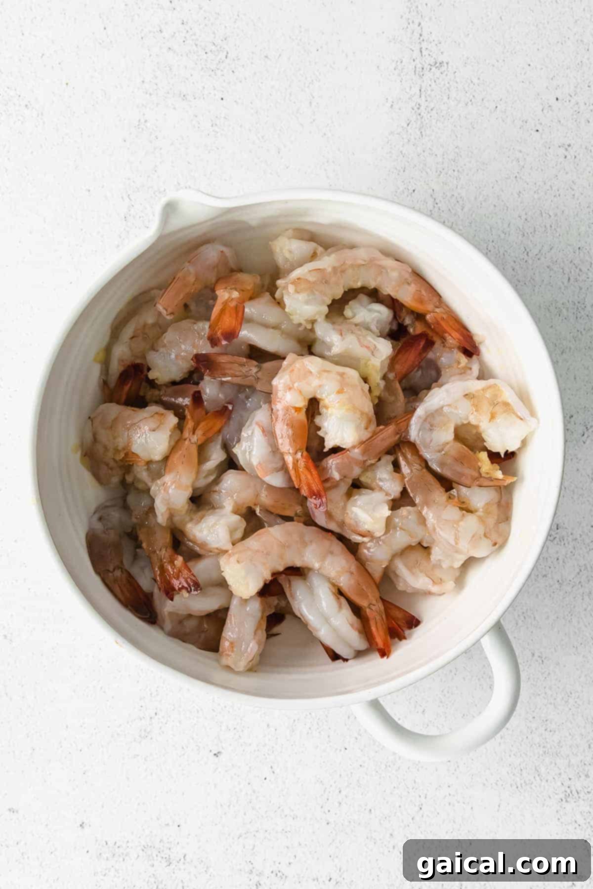 Zesty Lemon Garlic Shrimp 4 Raw jumbo shrimp ready for marinating in a bowl, illustrating the initial step of the sautéed shrimp recipe.