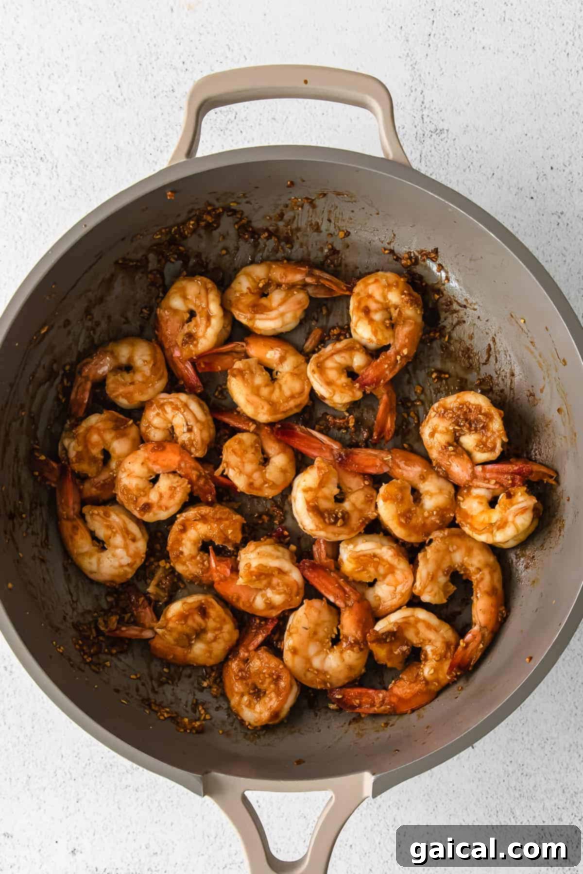 Zesty Lemon Garlic Shrimp 6 A serving of sautéed shrimp garnished with fresh herbs and sesame seeds in a pan, ready to be enjoyed.