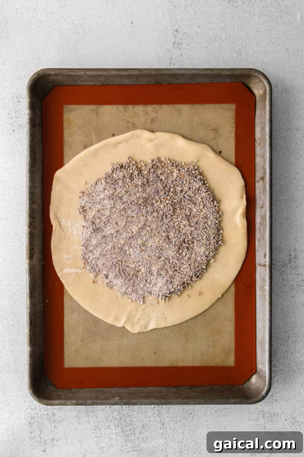 Pecan crumble mixture sprinkled over an unbaked pie crust, leaving space around the edges.
