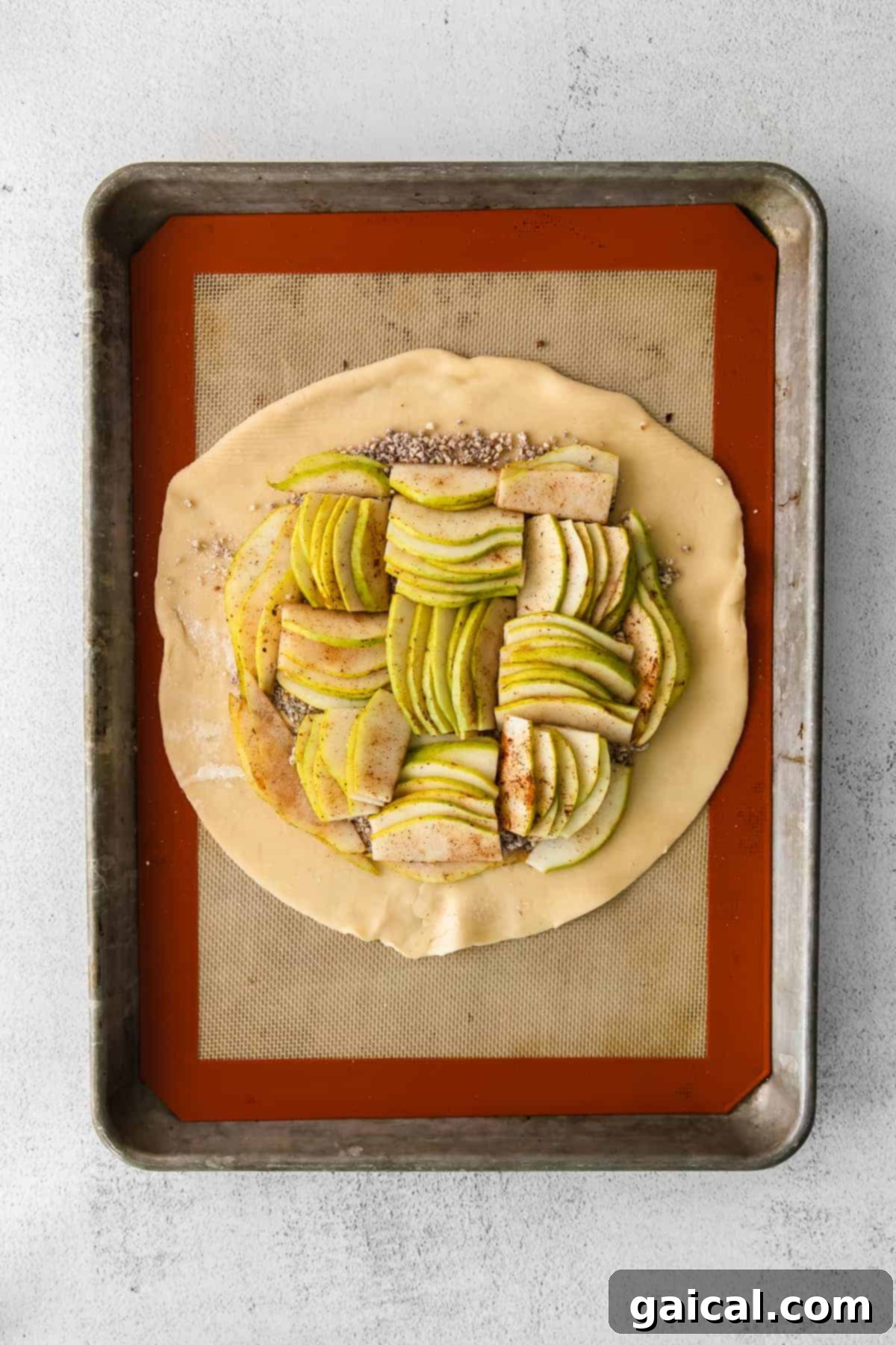 Layered pear slices arranged in the center of a pie crust, with the edges folded over to form a galette.