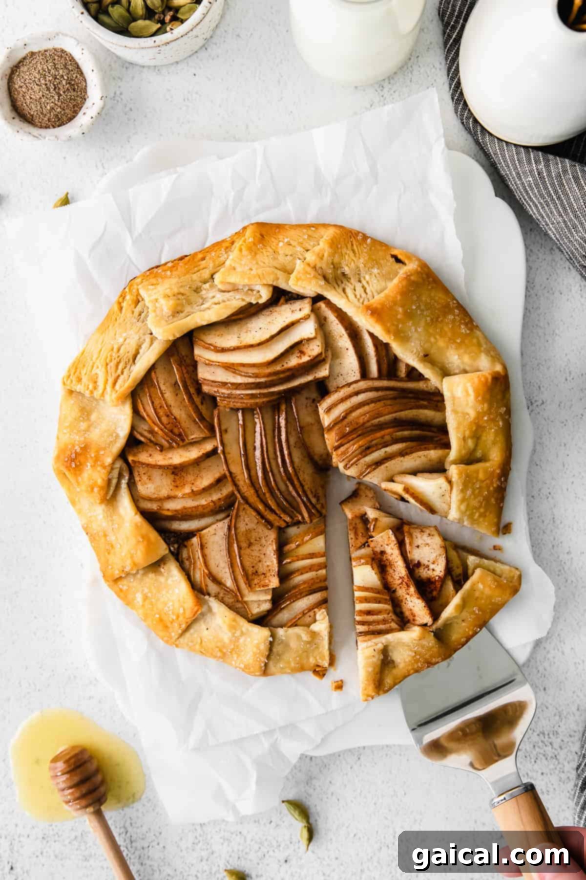 A slice of honey pear galette being removed from the pan with a spatula, revealing its crispy crust and pear filling.