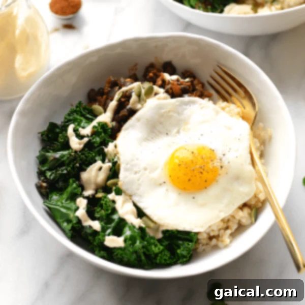 A visually appealing savory breakfast bowl featuring a runny fried egg over a bed of brown rice and dark green kale.