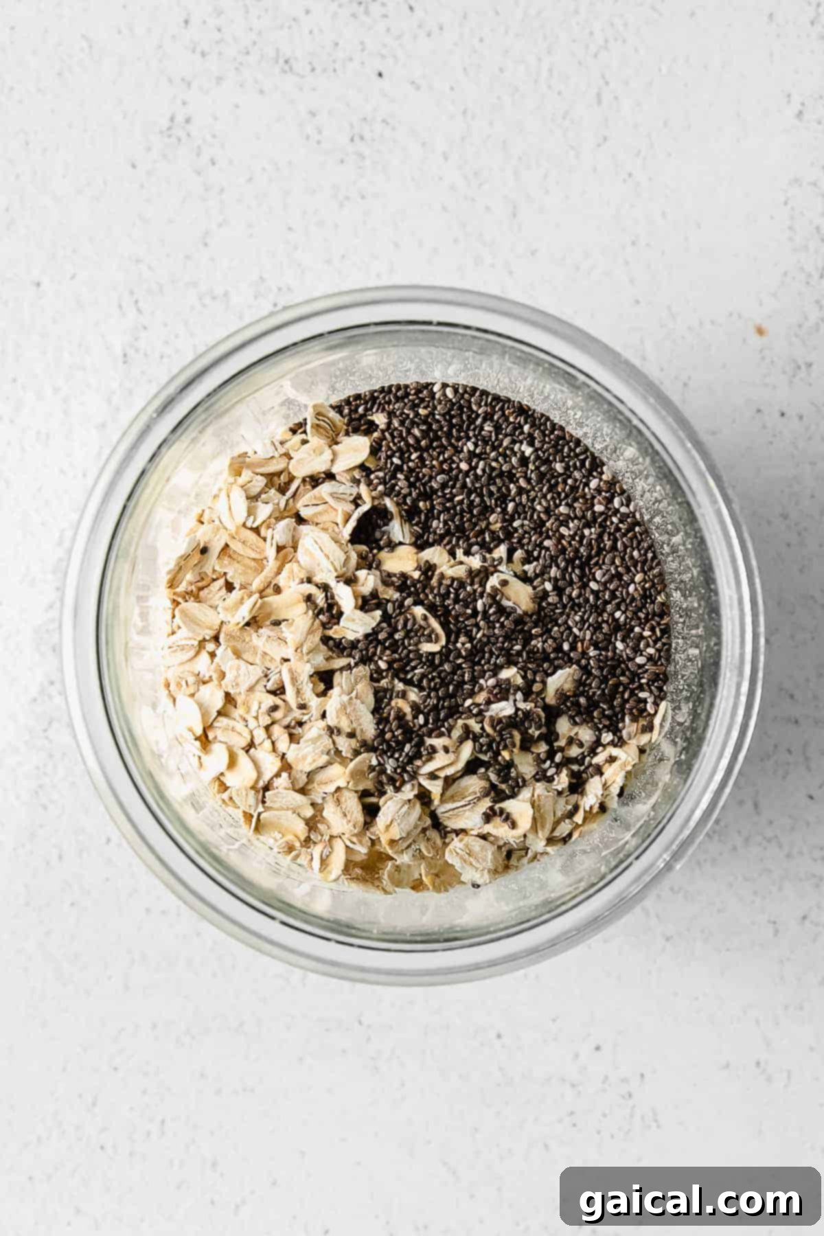 A jar filled with mixed ingredients for overnight oats, before chilling.