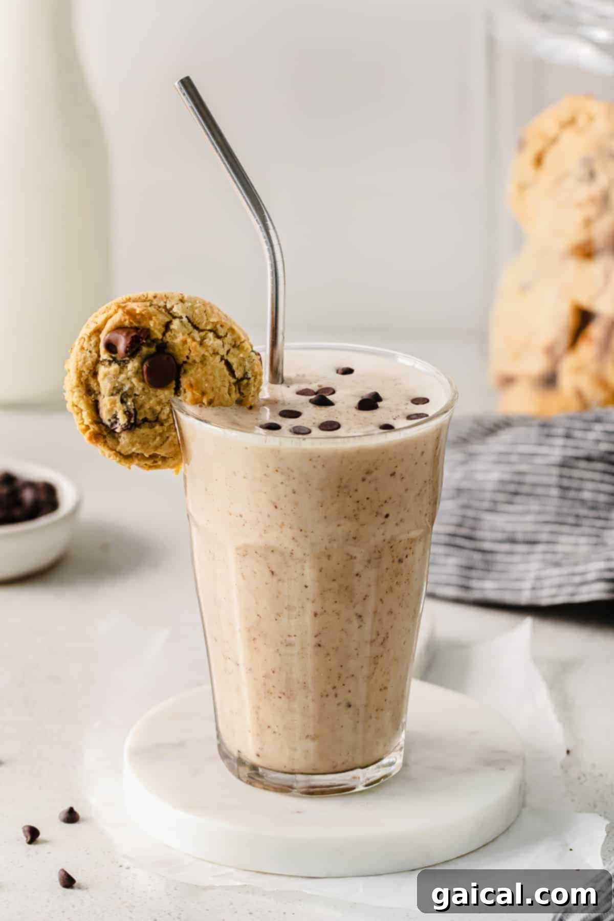 A delicious chocolate chip cookie dough smoothie served in a glass, with a real chocolate chip cookie elegantly placed on the rim, inviting a taste.