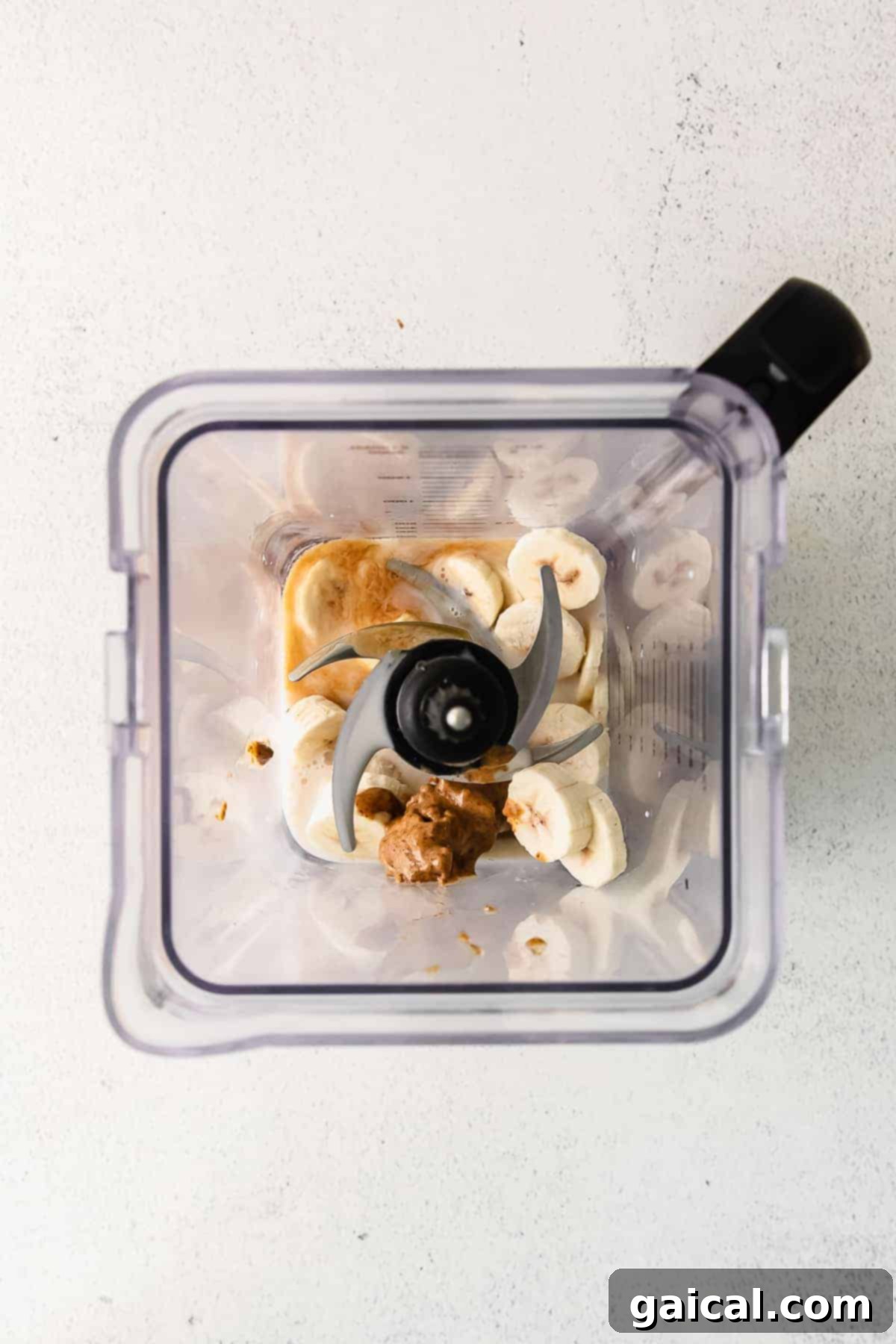 All the vibrant ingredients for a cookie dough blizzard smoothie are shown beautifully arranged inside a blender, poised for blending into a creamy mixture.