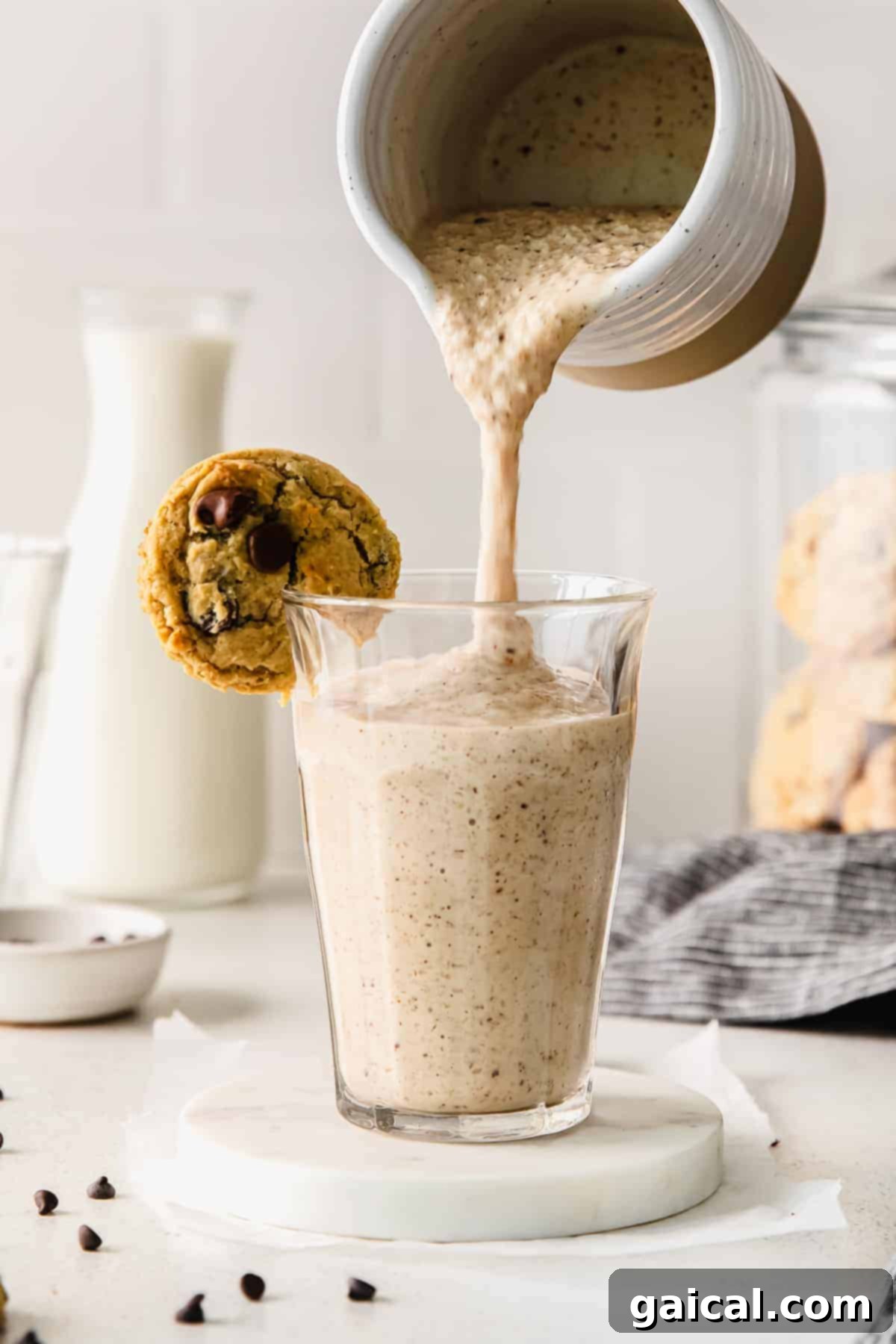 A smooth and creamy cookie dough smoothie being poured into an elegant clear glass, promising a refreshing and indulgent treat.