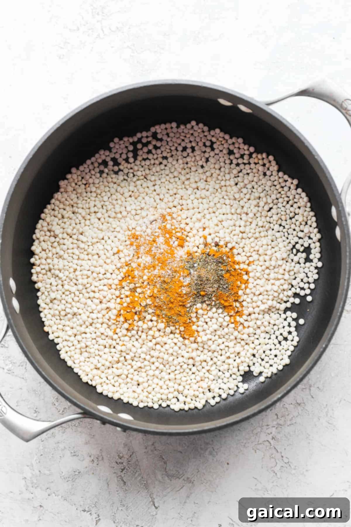 Zesty Lemon Garlic Israeli Couscous with Creamy Feta 3 Israeli couscous toasting with aromatic spices in a dutch oven, enhancing its nutty flavor before cooking.