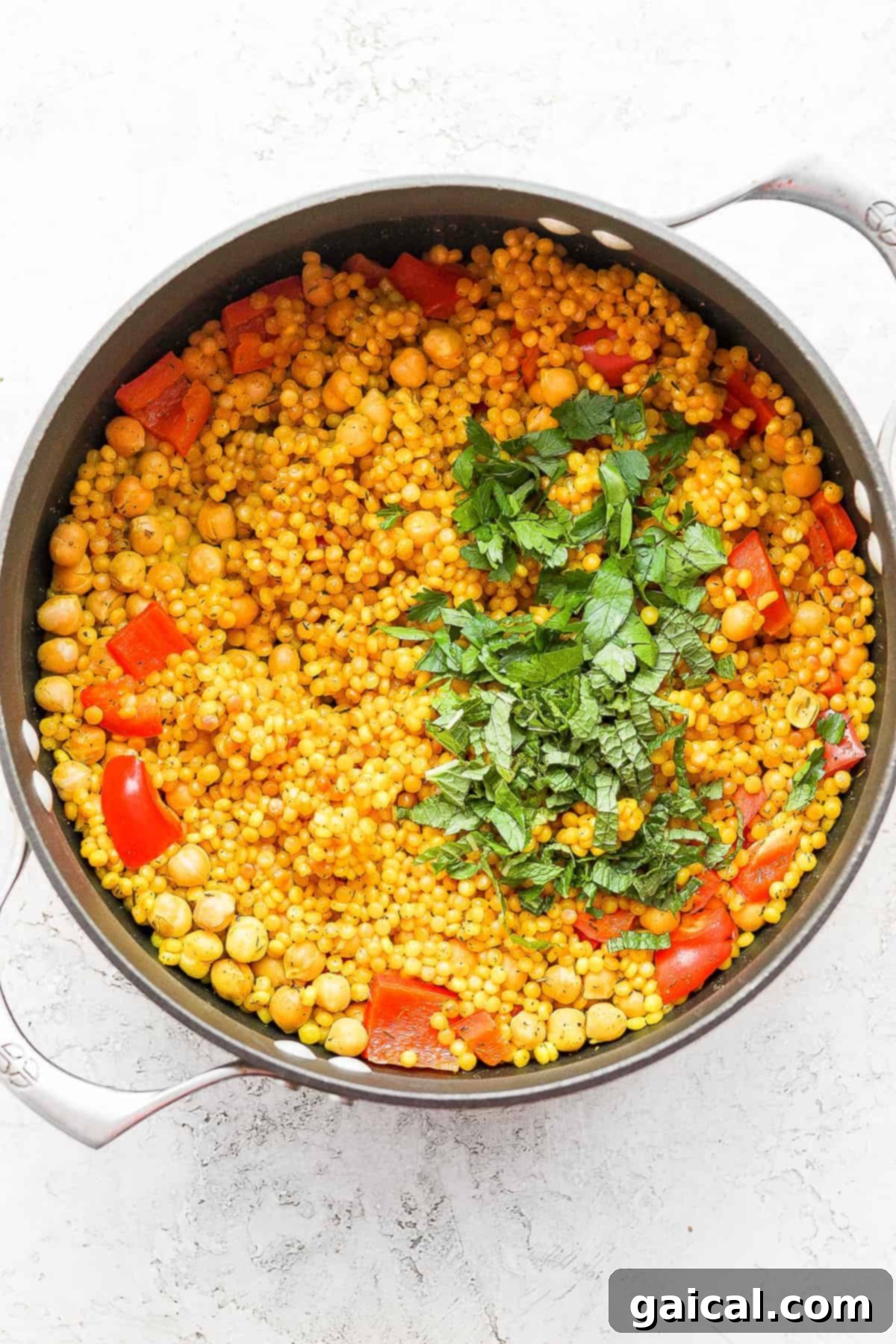 Zesty Lemon Garlic Israeli Couscous with Creamy Feta 6 Freshly chopped herbs scattered over the finished Lemon Garlic Israeli Couscous, adding a final touch of vibrant color and fresh aroma before serving.