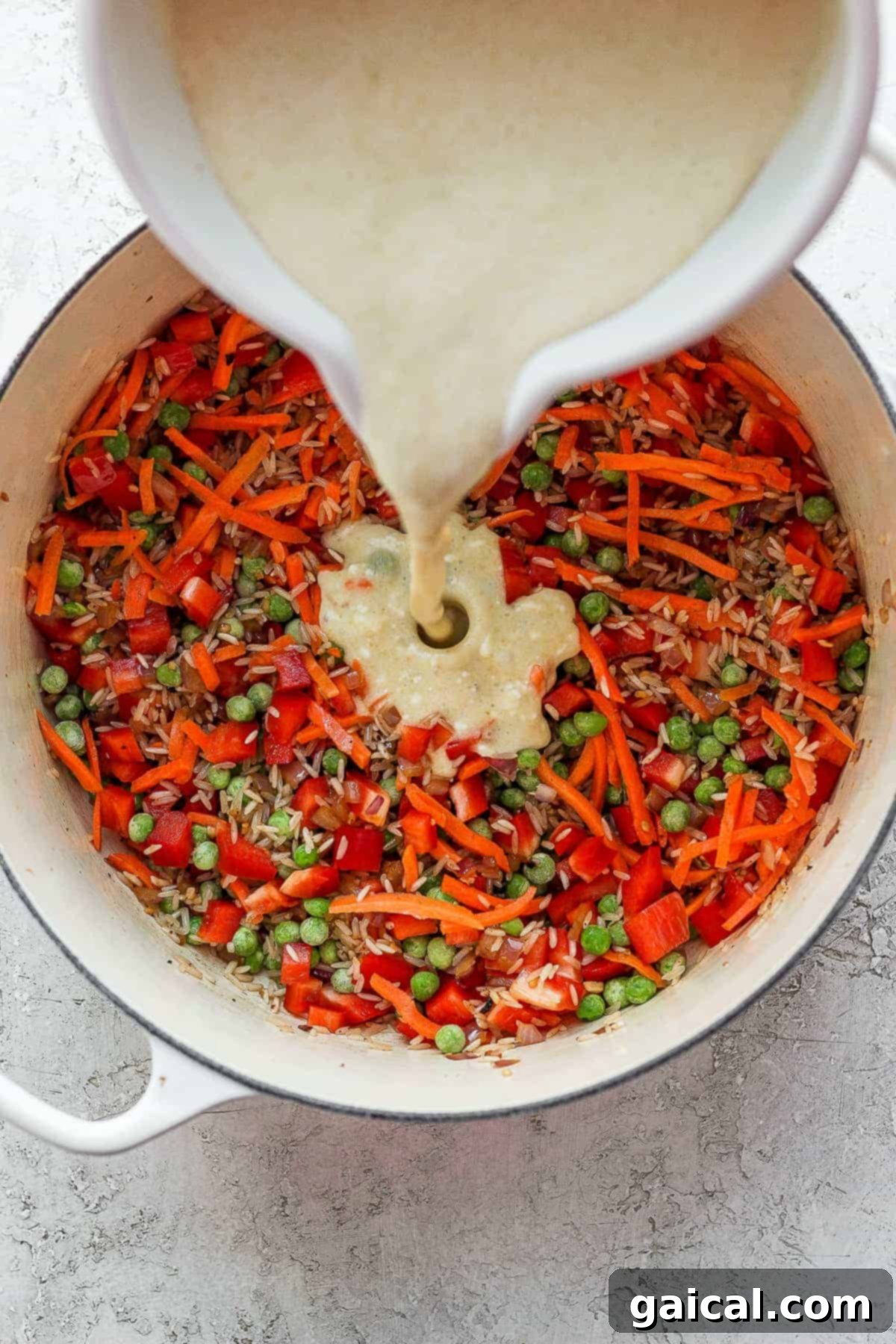Adding Curry Sauce to Vegetables Chef pouring rich, creamy coconut curry sauce over a mix of aromatic vegetables and rice in a Dutch oven, ready for baking.