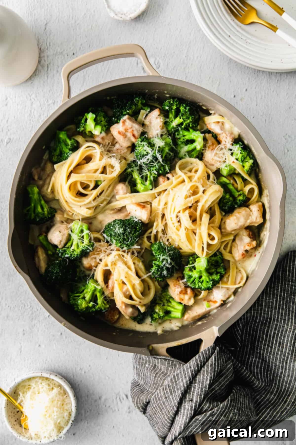 Creamy chicken broccoli alfredo pasta served in a skillet, garnished with fresh parsley and parmesan cheese.