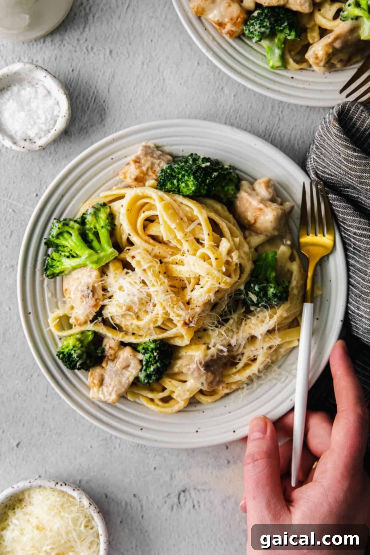 A serving of chicken broccoli alfredo pasta on a white plate, ready to be enjoyed.