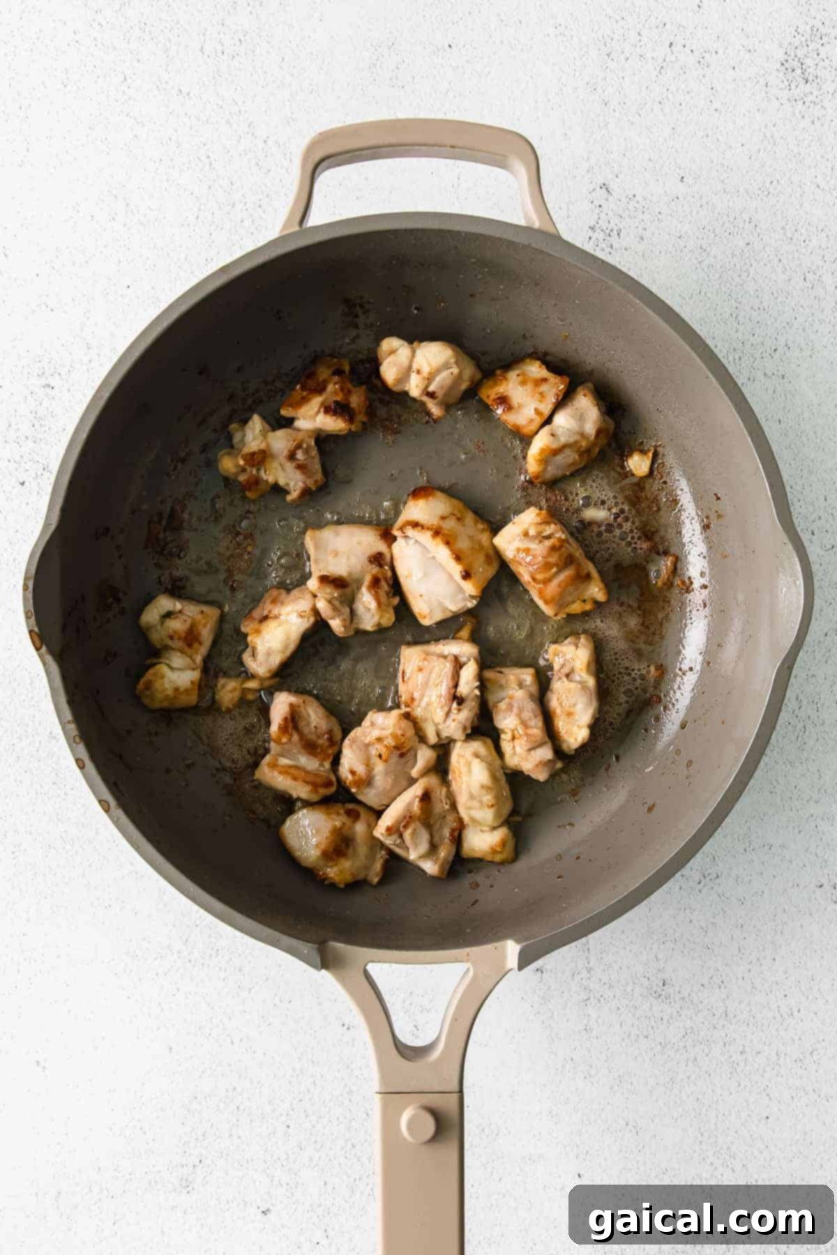 Chicken thighs searing to a golden brown in a hot skillet, ready to add rich flavor to the alfredo.